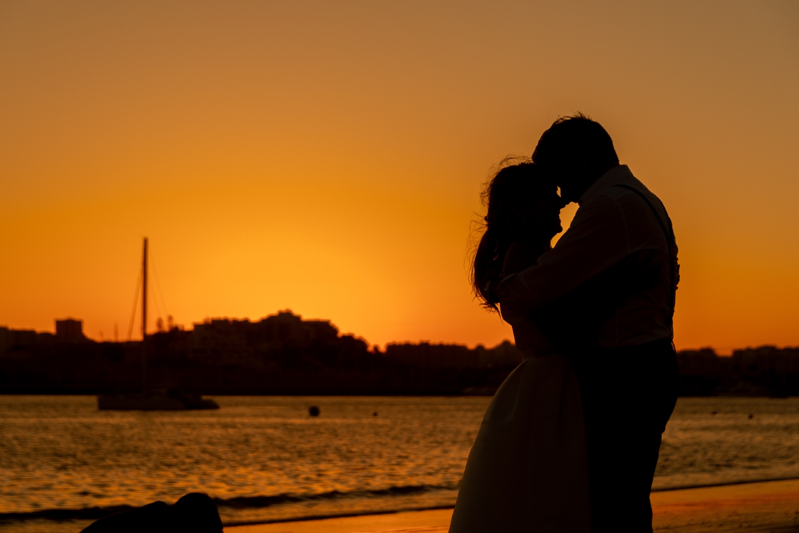 man and woman standing near sea during sunset