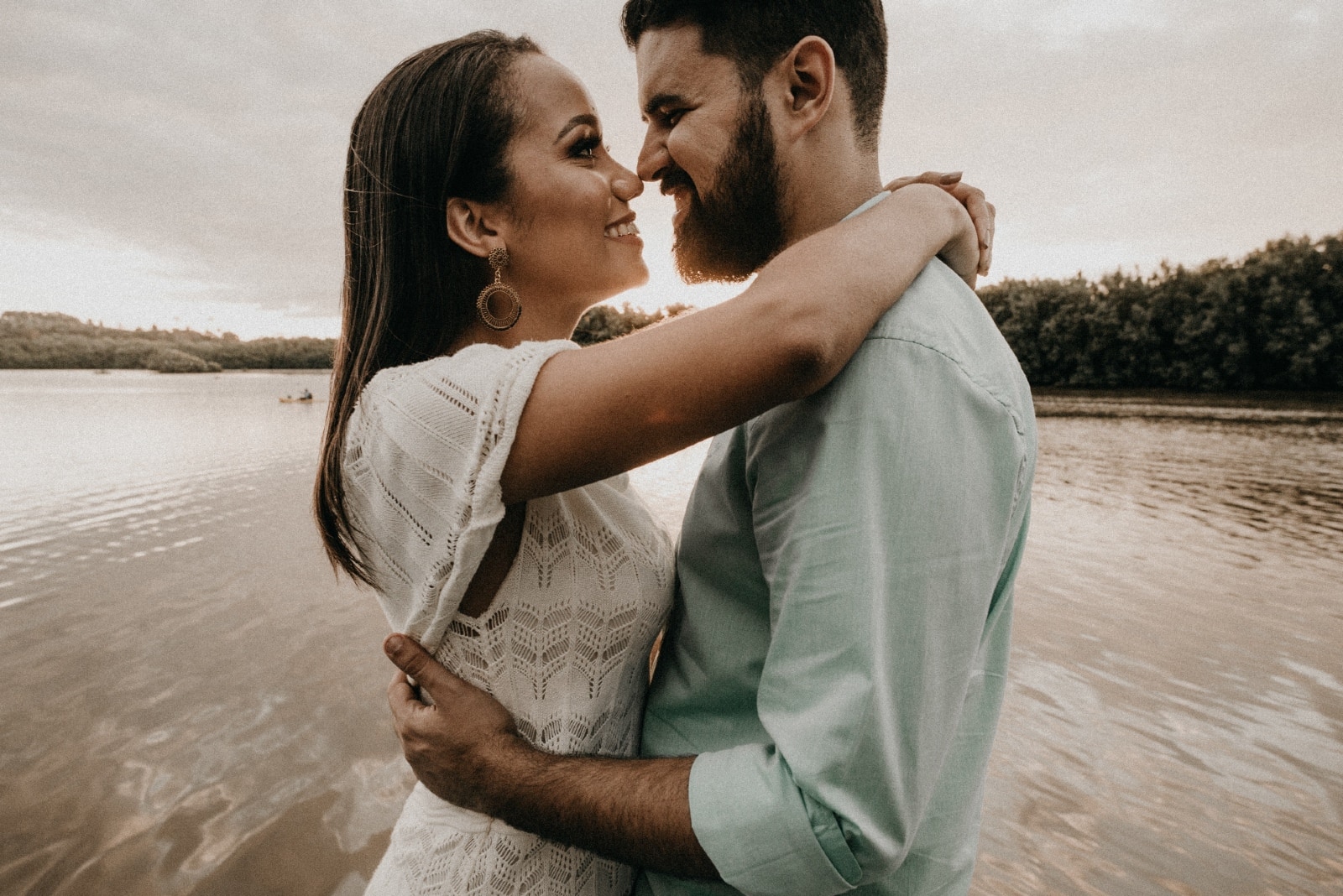 man and woman hugging while standing near water