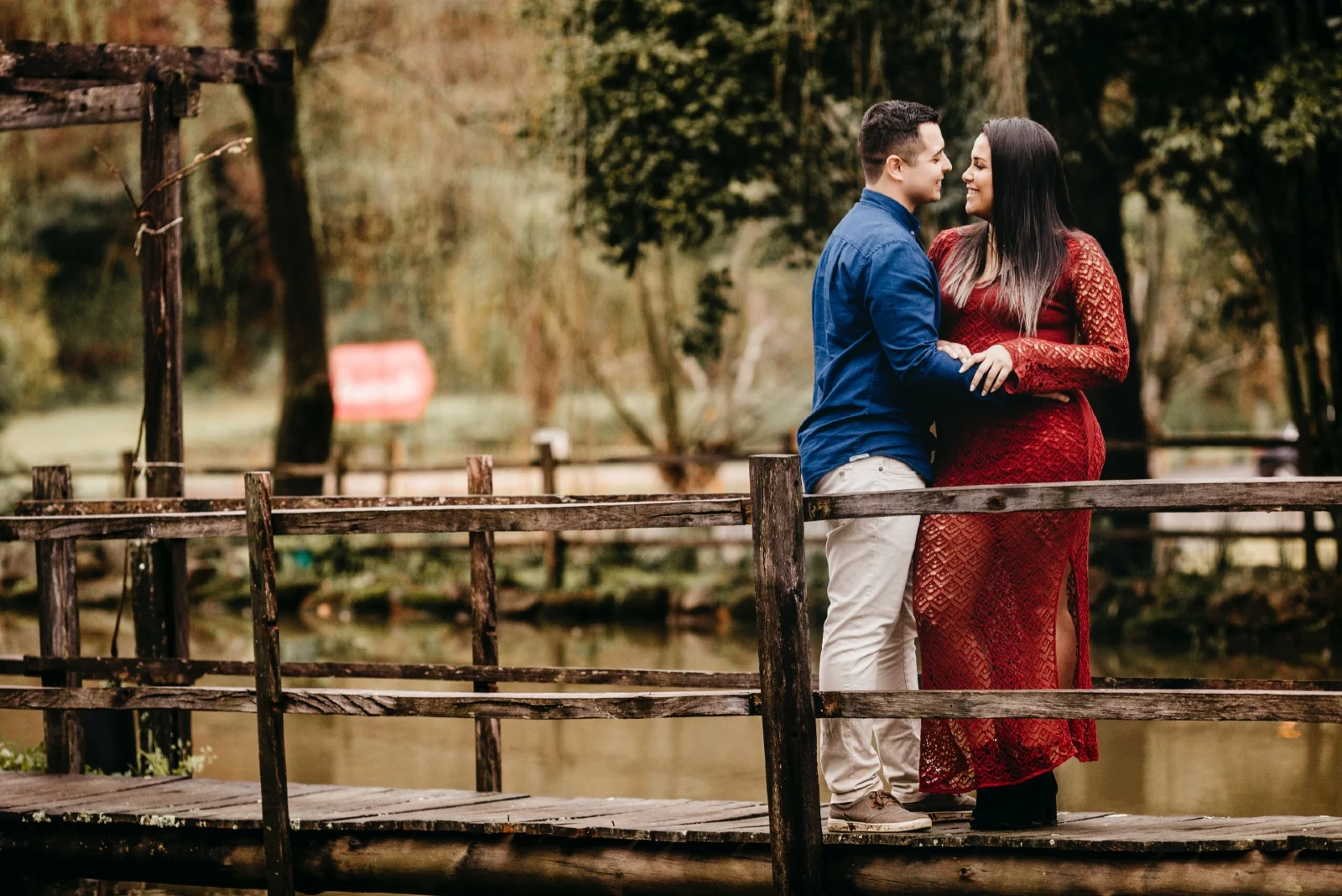 man and woman hugging while standing on bridge