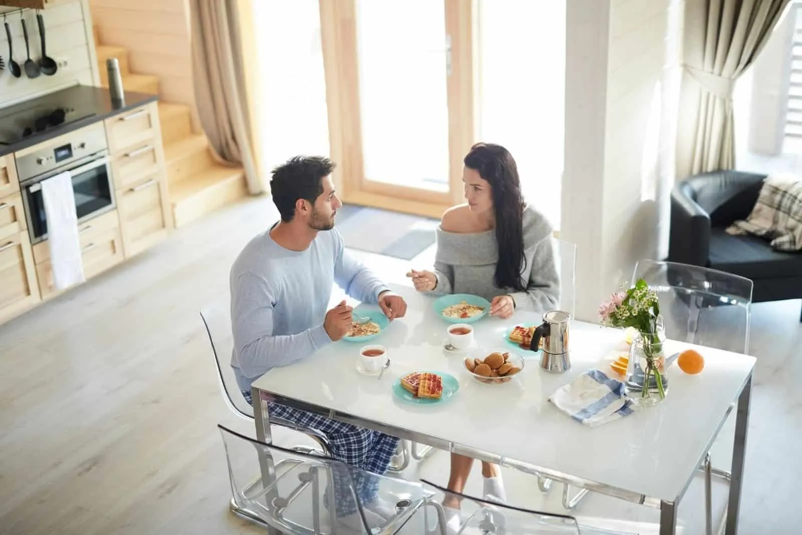 couple taking breakfast by the table in the kitchen and seriously talking 