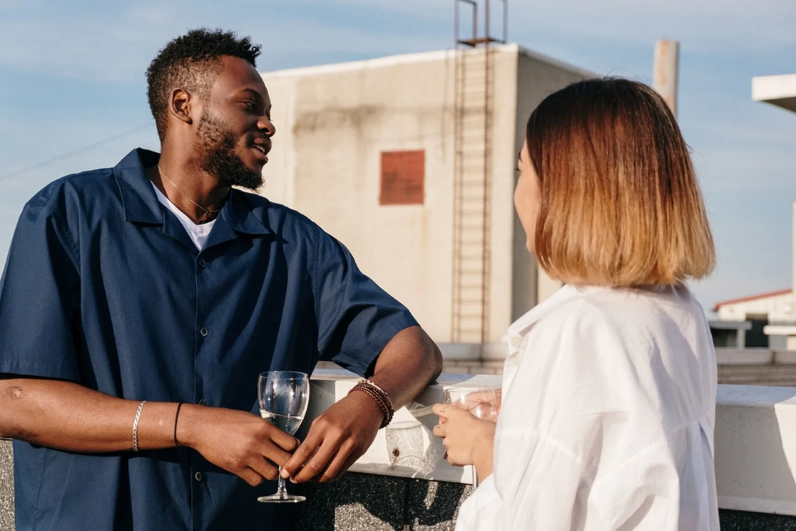 man and woman talking while standing on rooftop