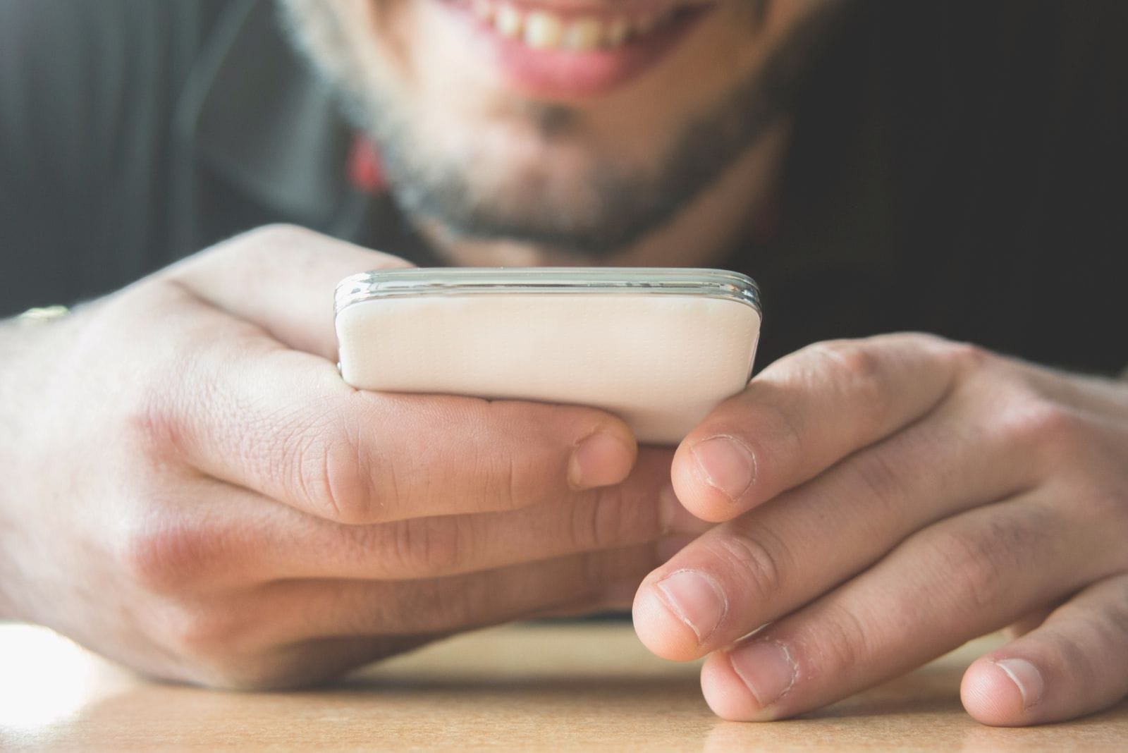 cropped image of a man texting in focus to the phone and hands