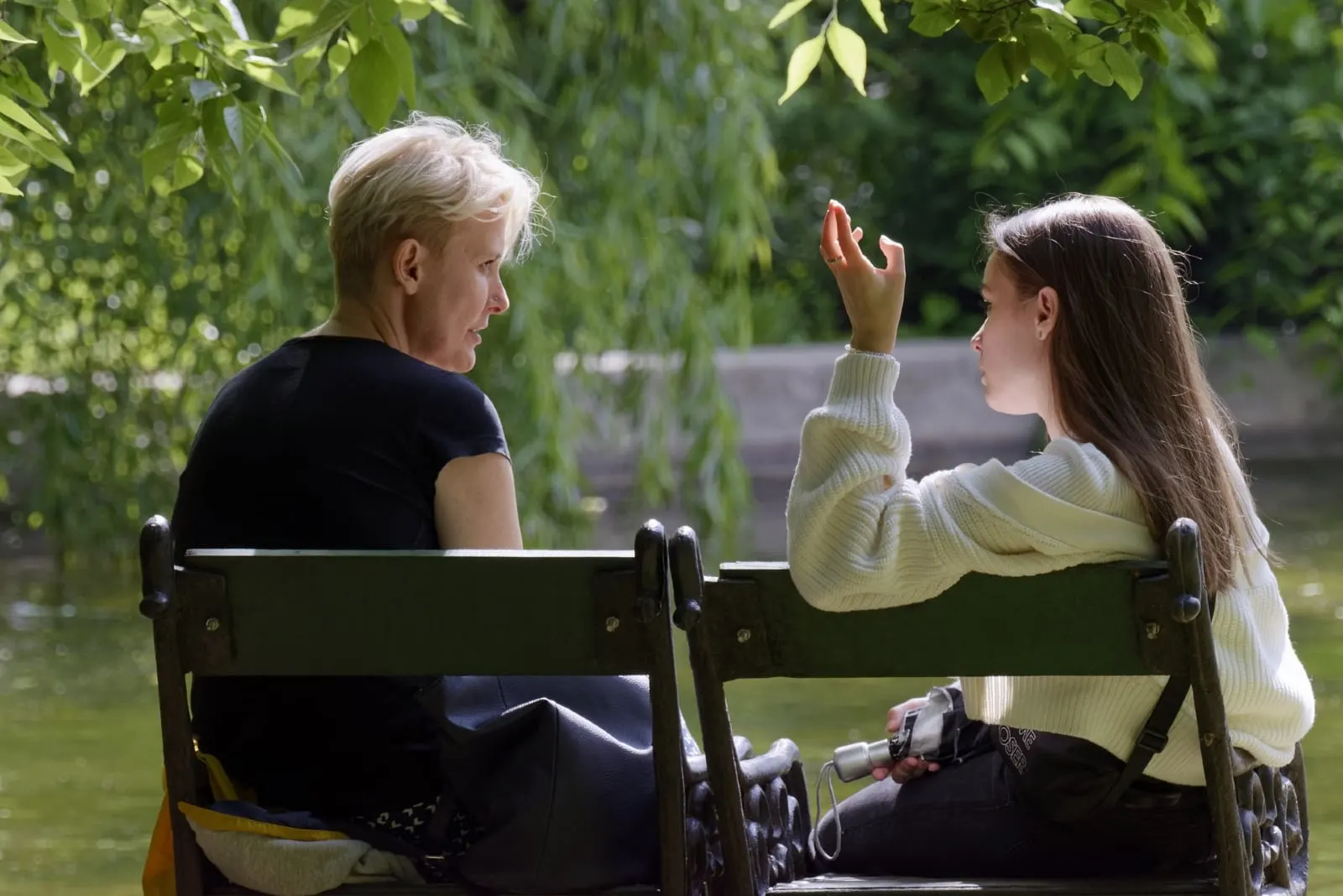 daughter talking to mother while sitting on bench