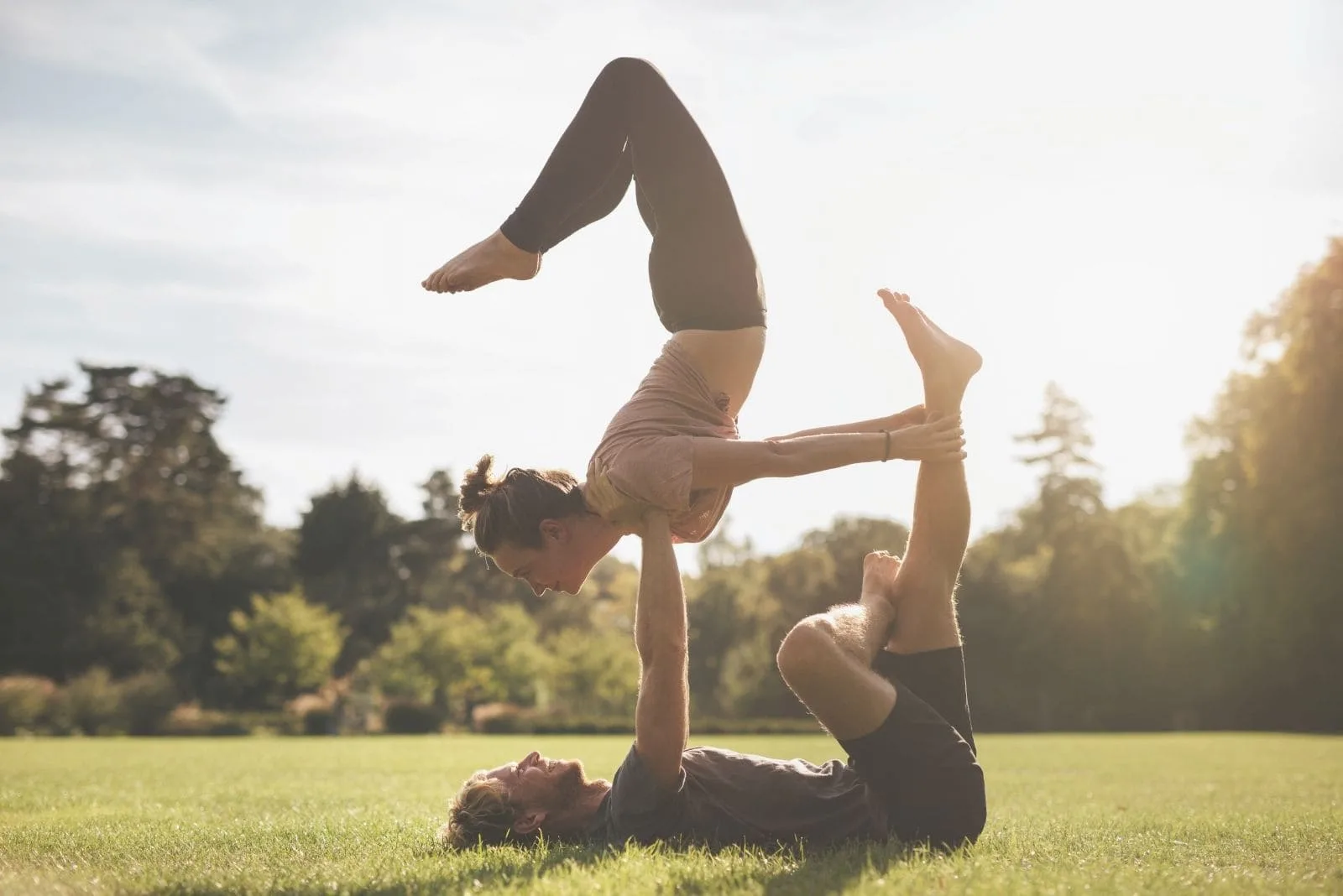 fit young couple doing acroyoga together on grass