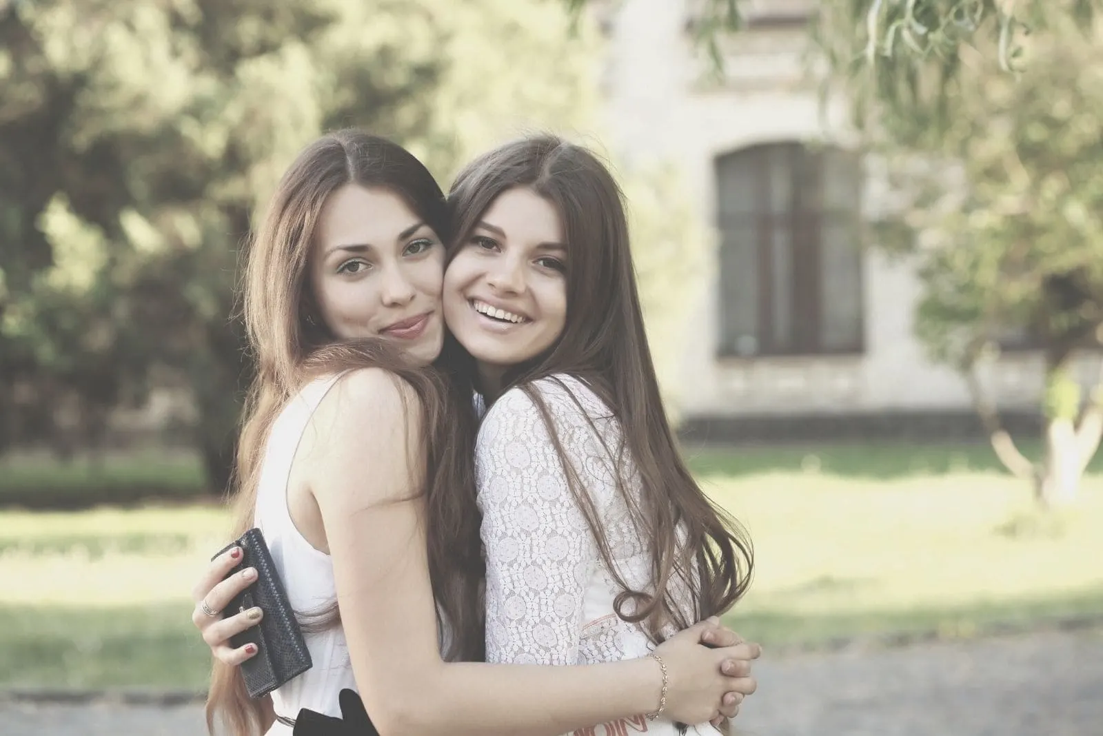 girlfriends hugging outdoors looking at the camera and smiling