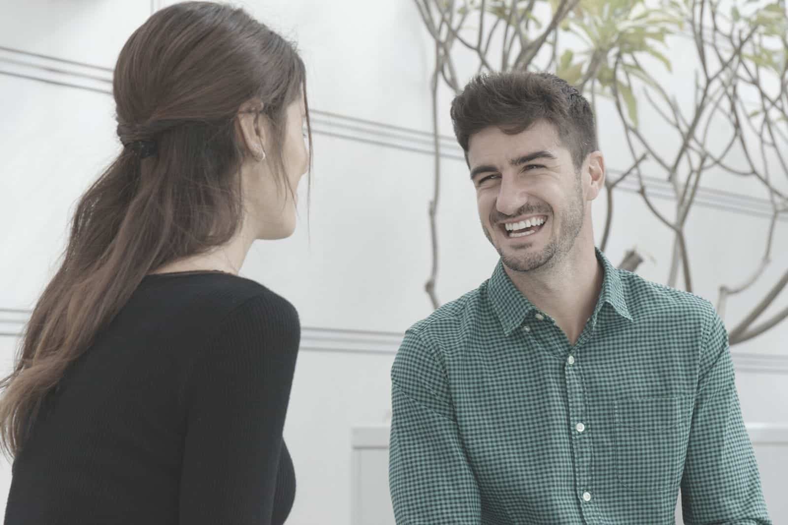 Feliz y alegre pareja hablando fuera de su casa