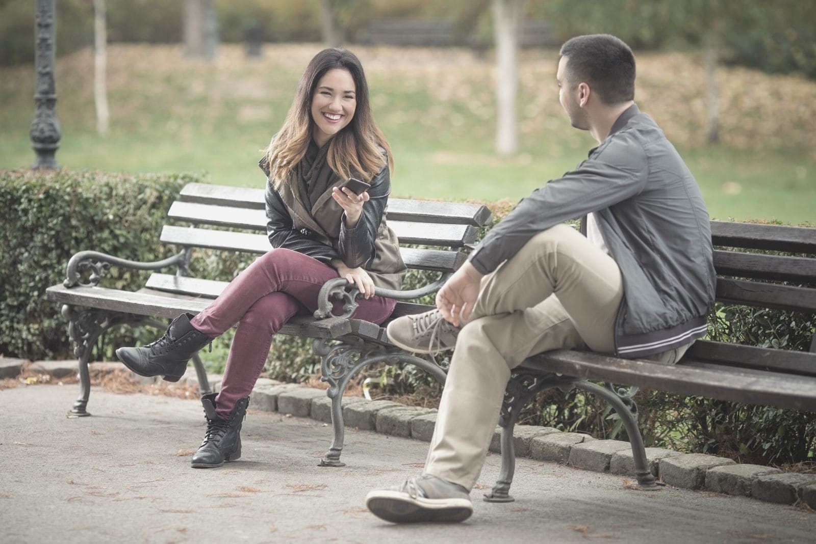 donna felice che sorride al ragazzo seduto vicino a lei nella panchina del parco