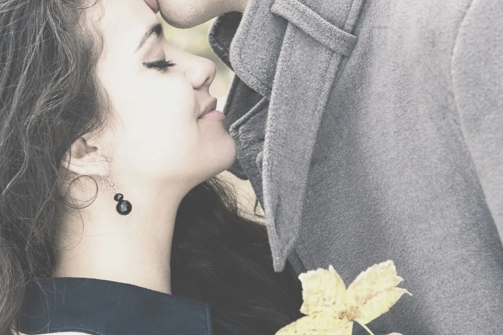 image of a passionate couple kissing with the woman holding yellow leaf