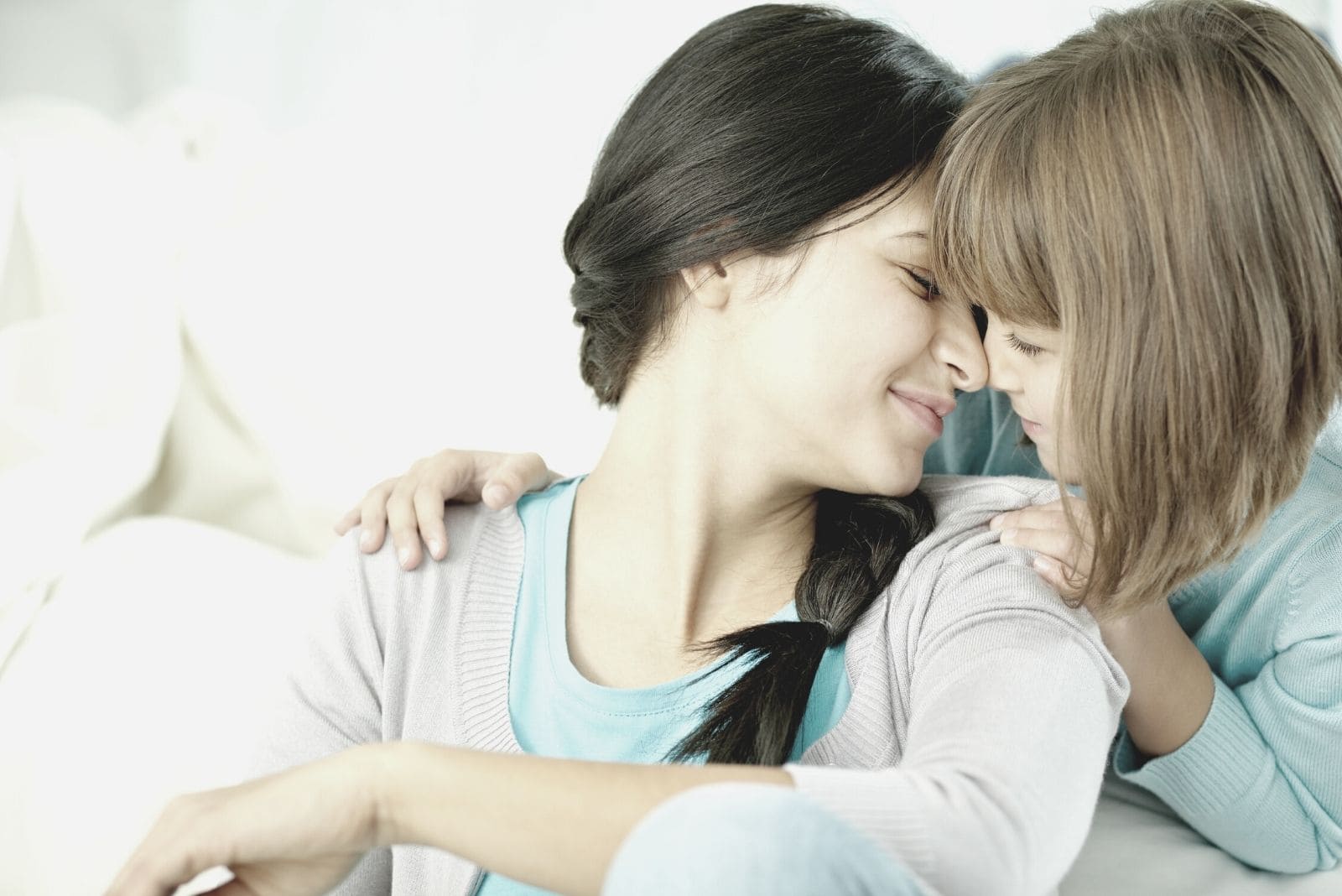 little girl cuddling with her young mother sitting