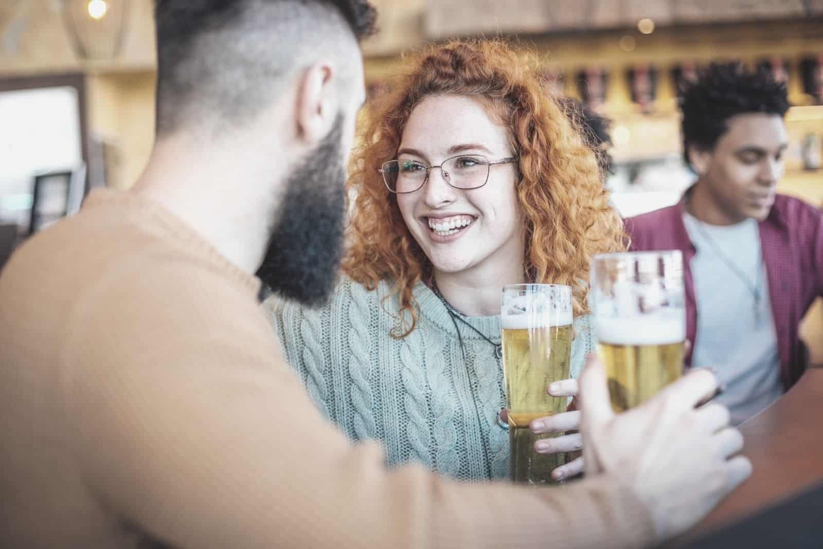 uomo e donna che bevono birra in un bar con gli amici 