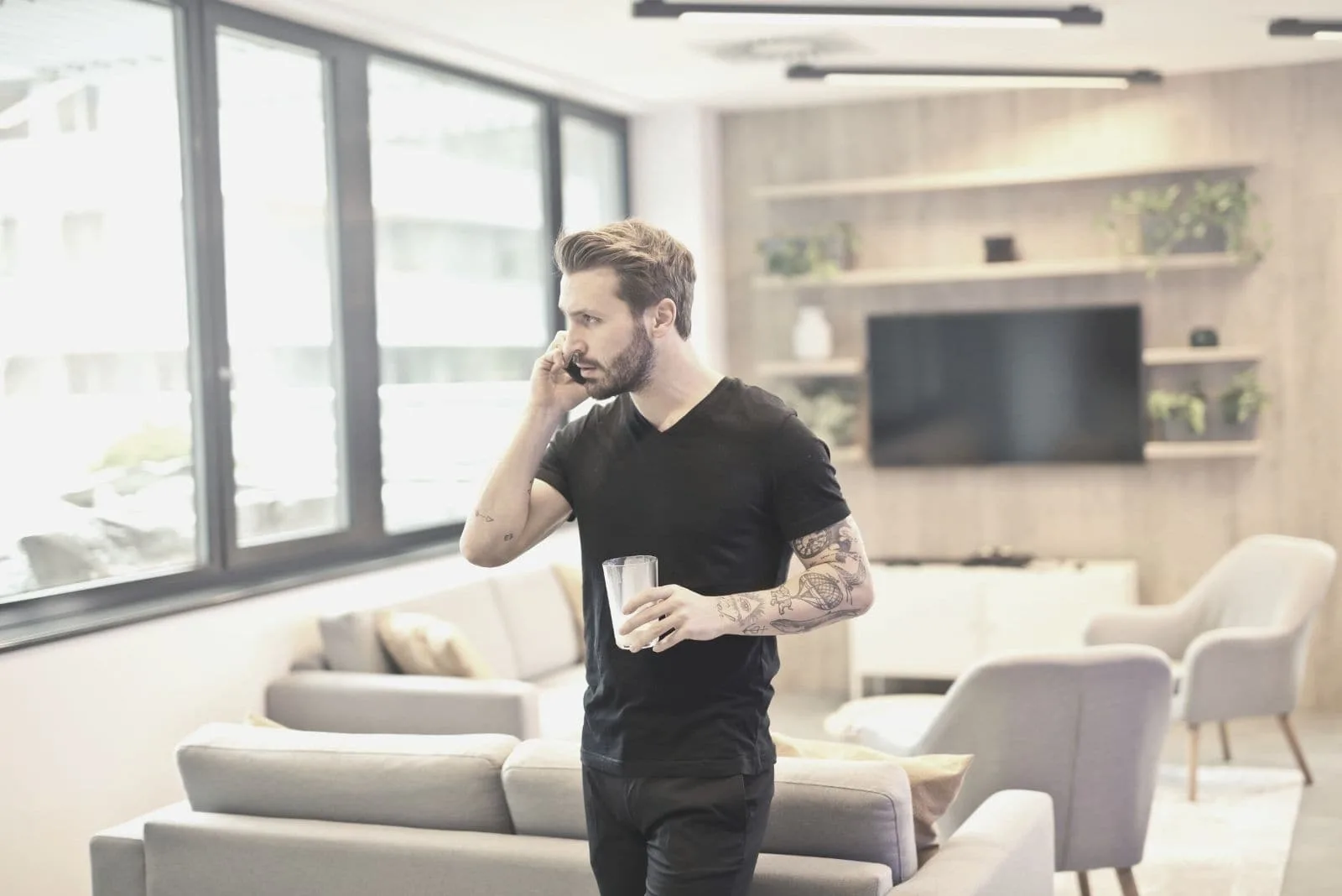 man calling on phone standing and holding glass inside the living room