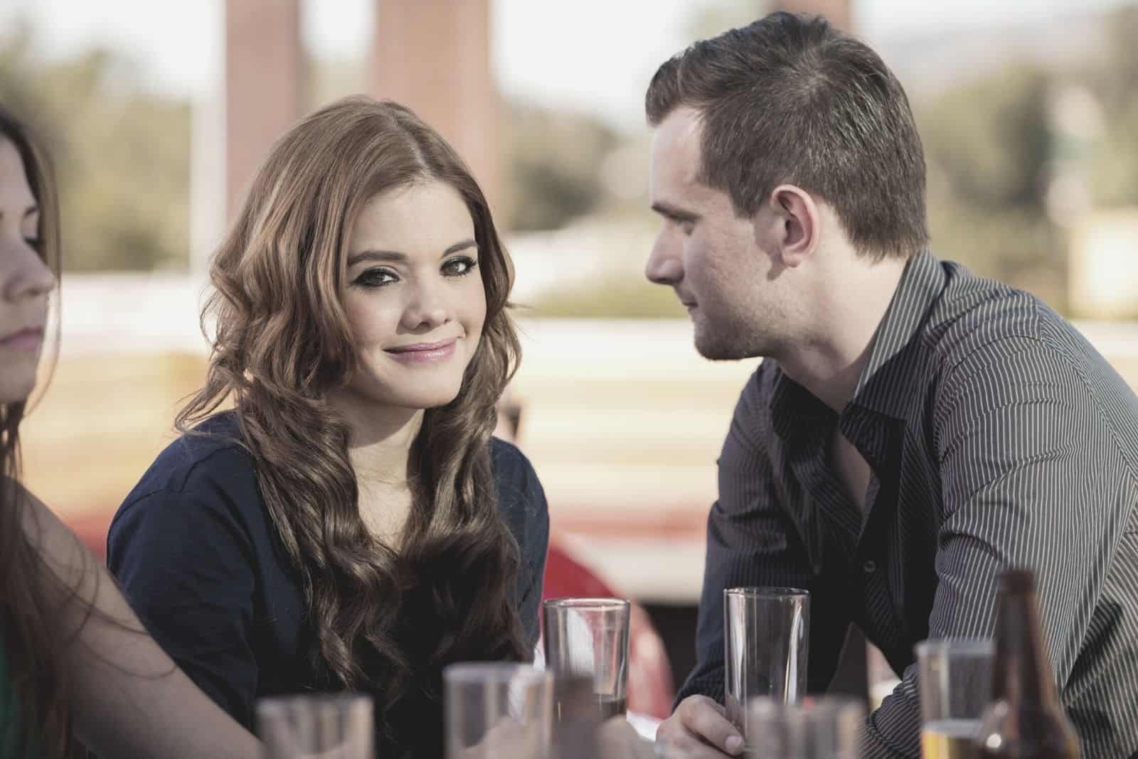 homme flirtant avec une femme tout en prenant un verre avec des amis à l'intérieur