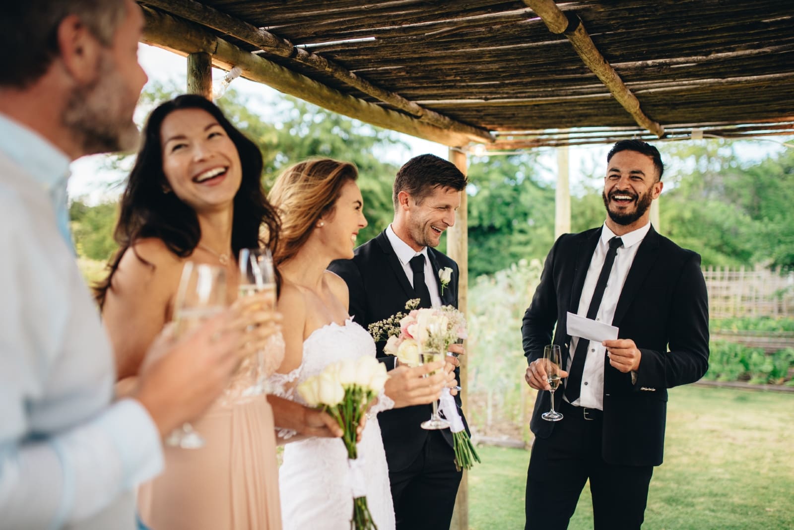 hombre sosteniendo un papel blanco cerca del novio y la novia