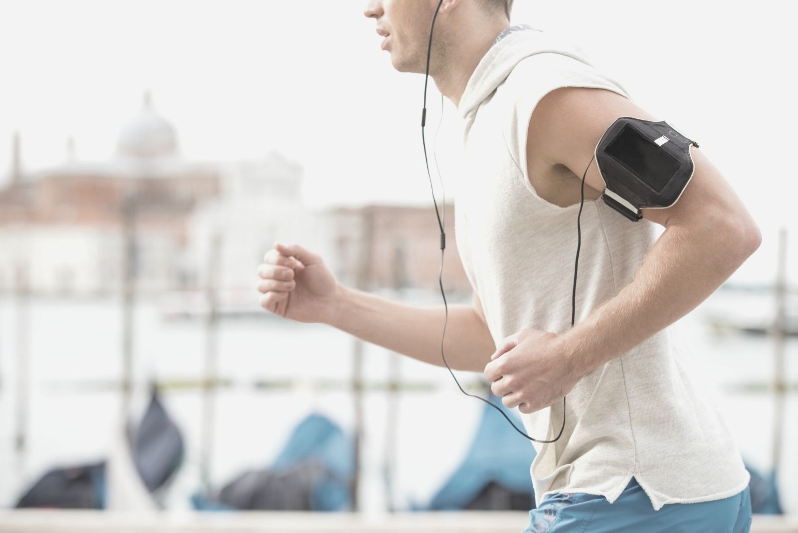 uomo che fa jogging all'aperto con cuffie e fascia da braccio in un'immagine ritagliata