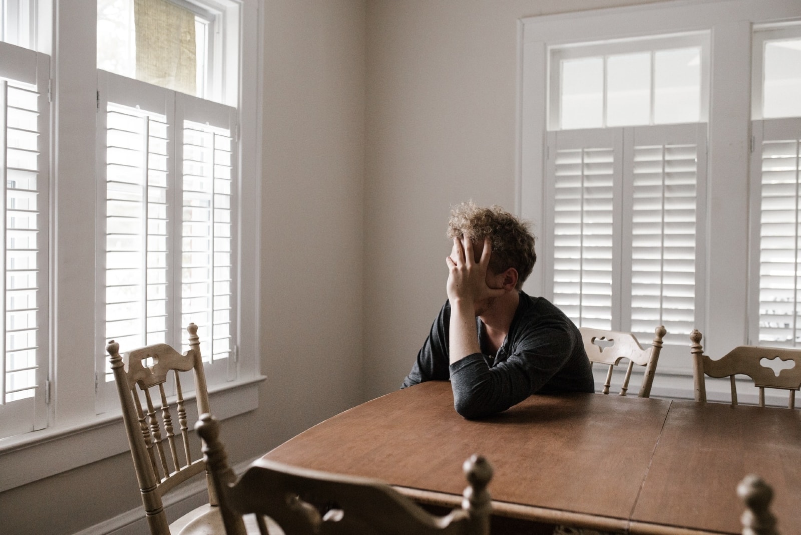 worried man in black shirt leaning on table