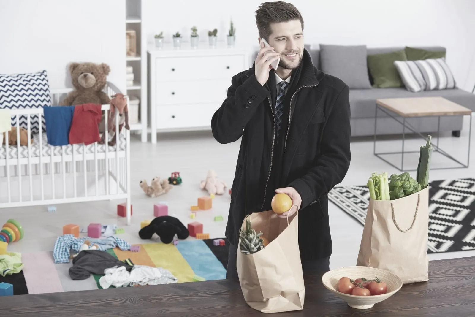 man putting down groceries on the dining table while answering a phone call