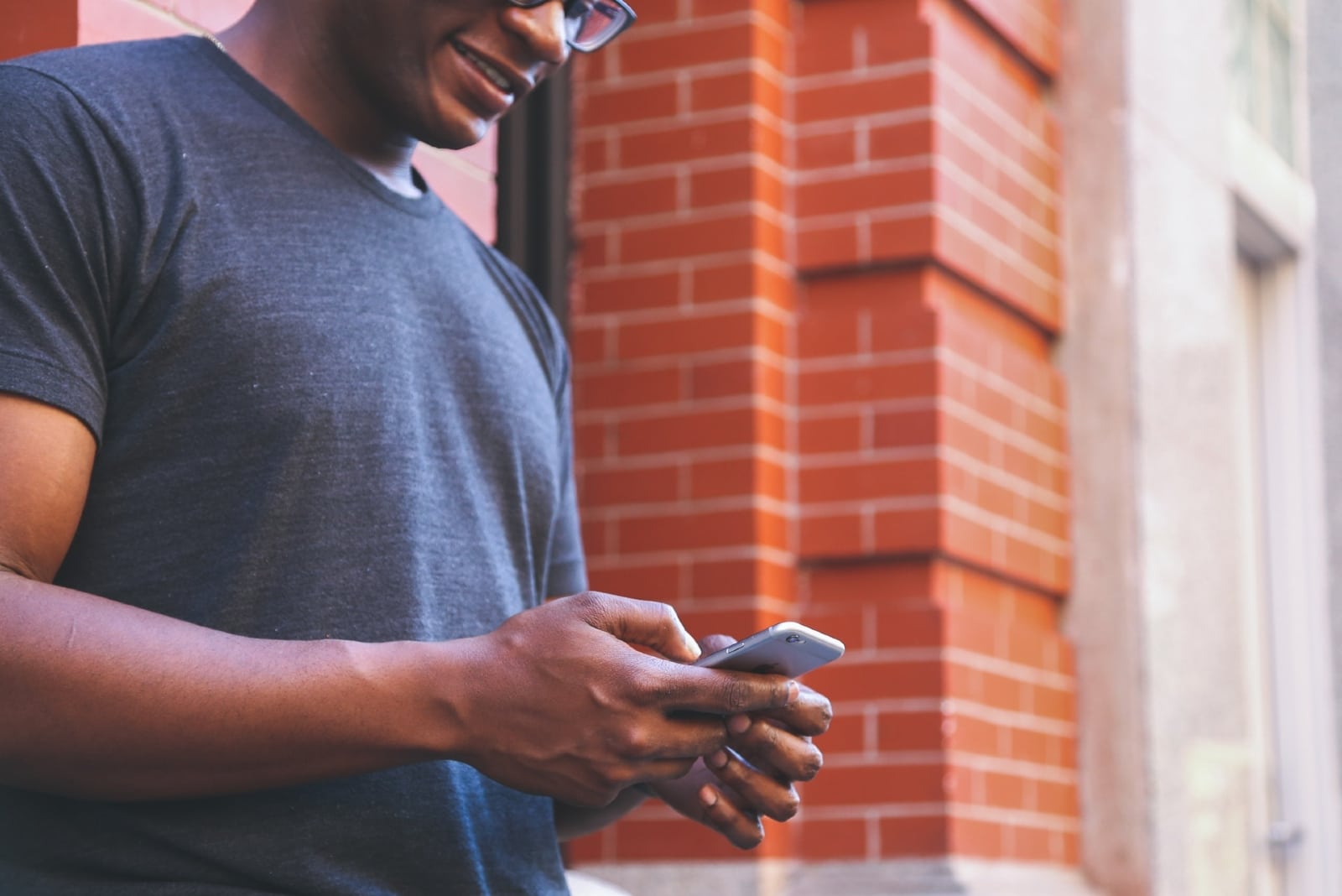 man using smartphone while standing near building