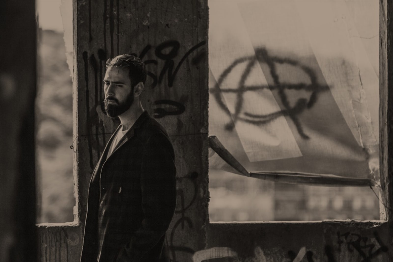 sad man with beard standing near wall