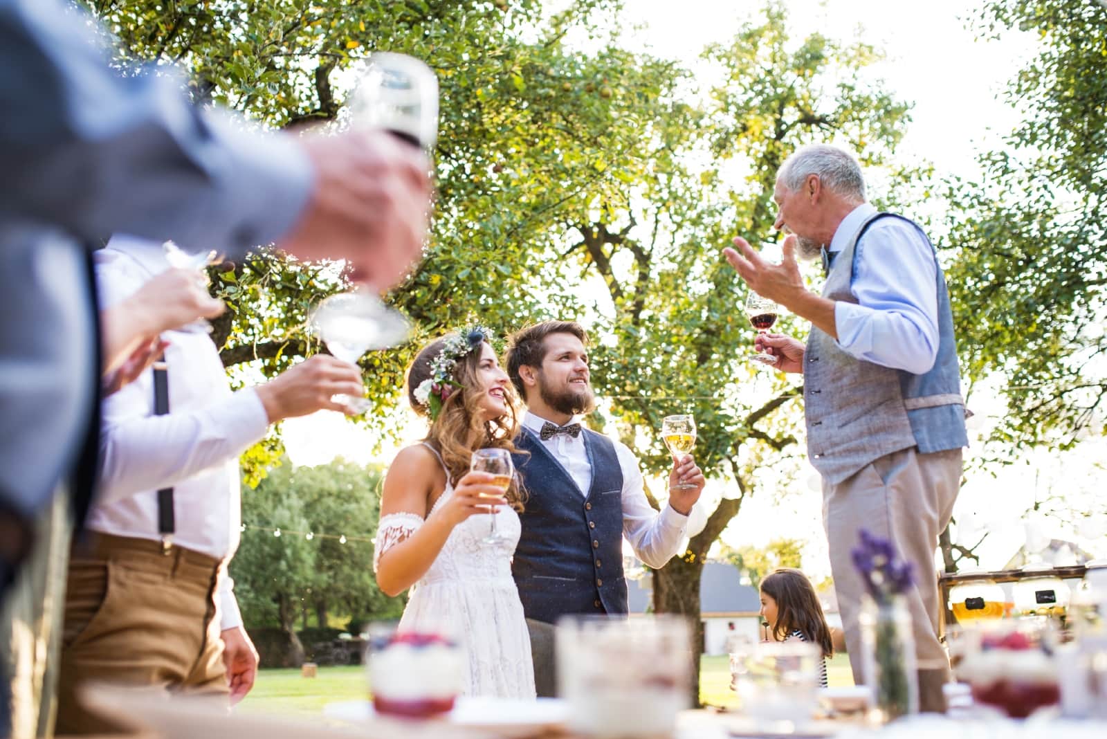 man talking to groom and bride while holding wine glass