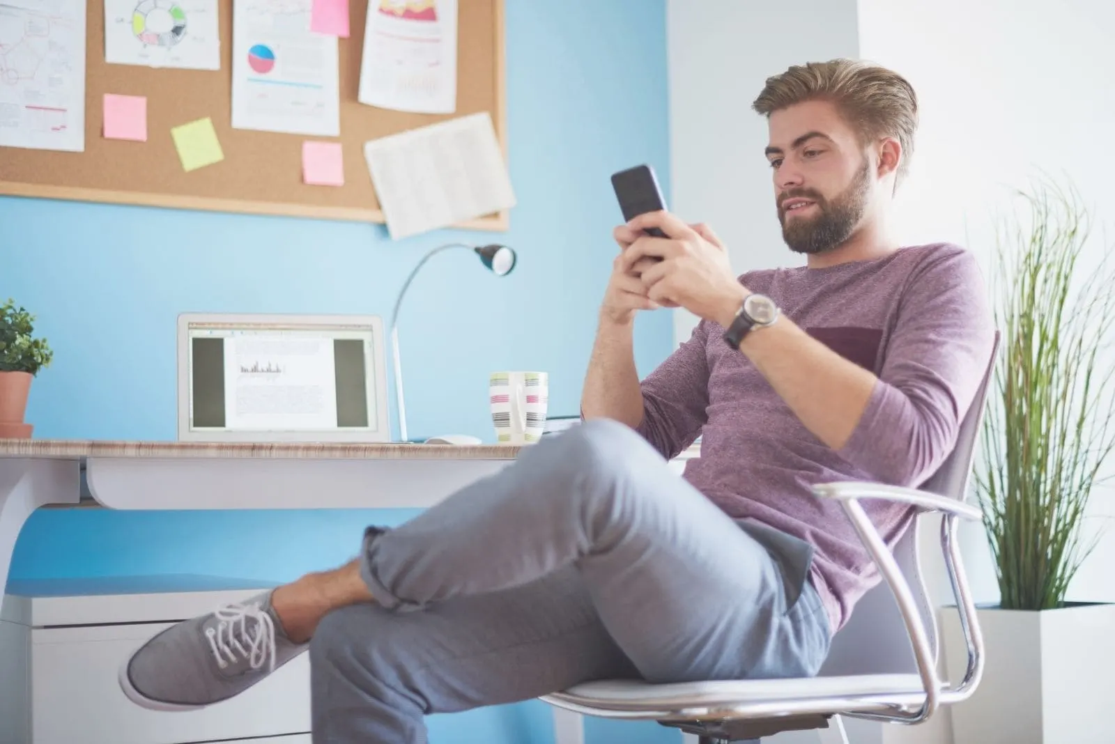 man texting in his mobile phone while sitting inside office 