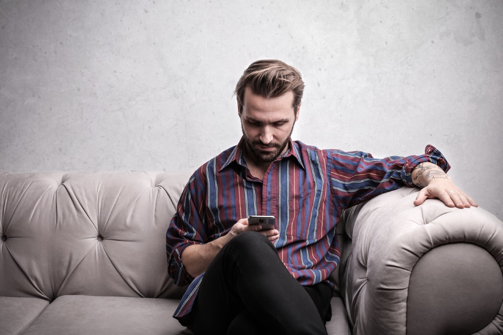 man using smartphone while sitting on sofa
