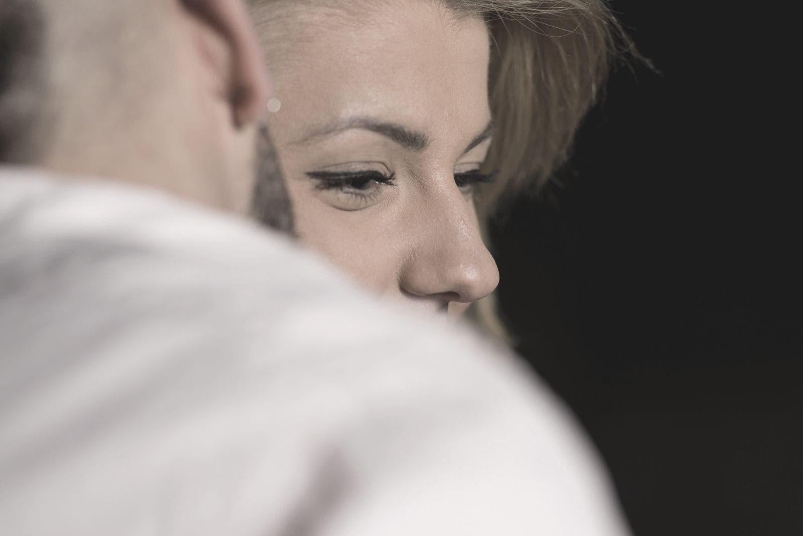 man whispering something to the woman's ear in close up photo