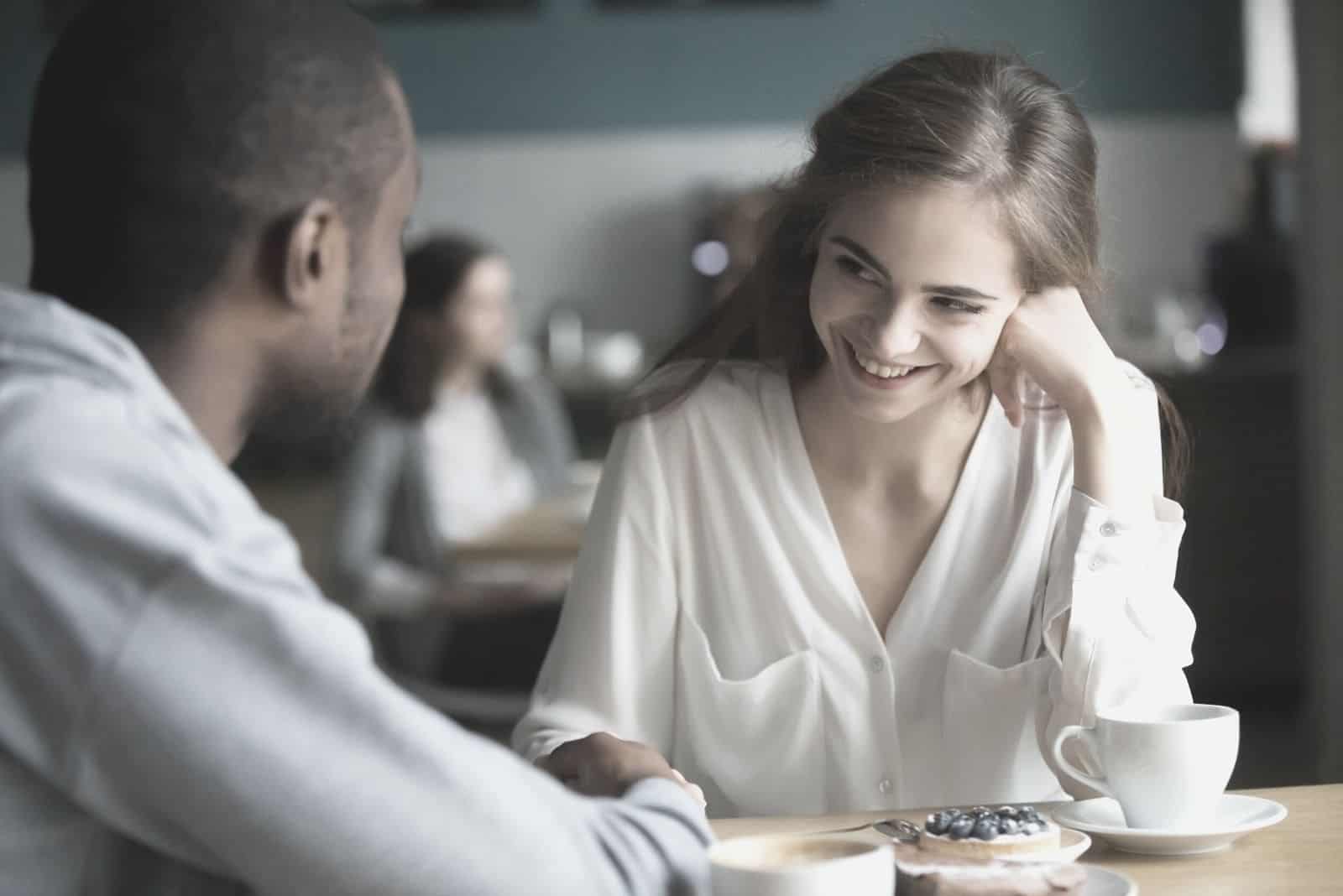 multiracial couple talking while having coffee break inside a cafe