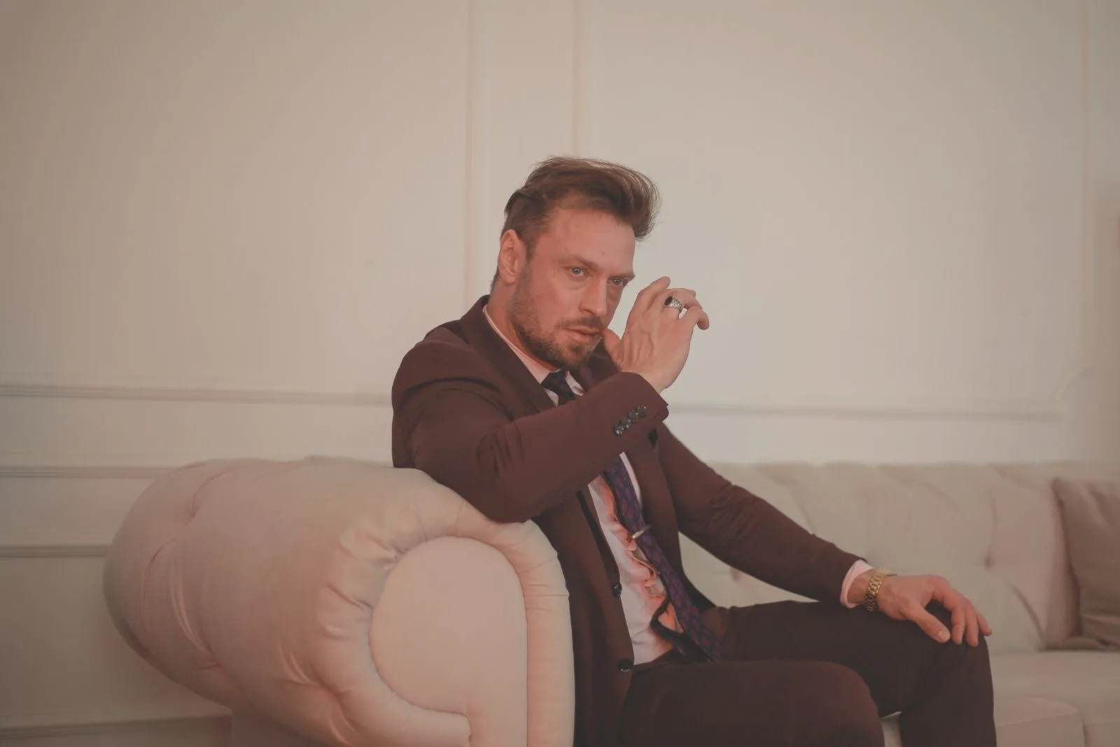 pensive man wearing a suit sitting on the sofa
