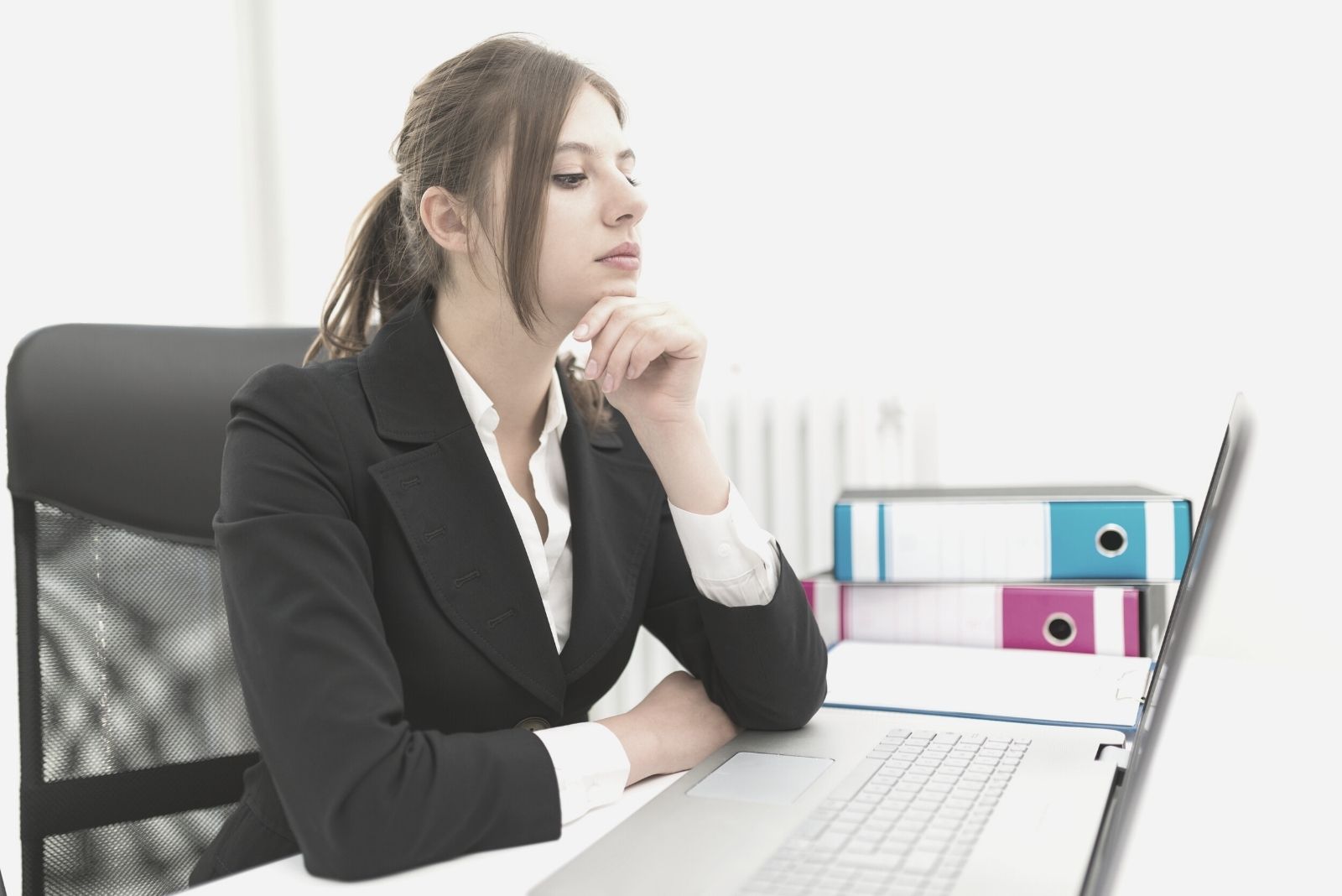 pensive office woman sitting by his table looking at the laptop and thinking deeply