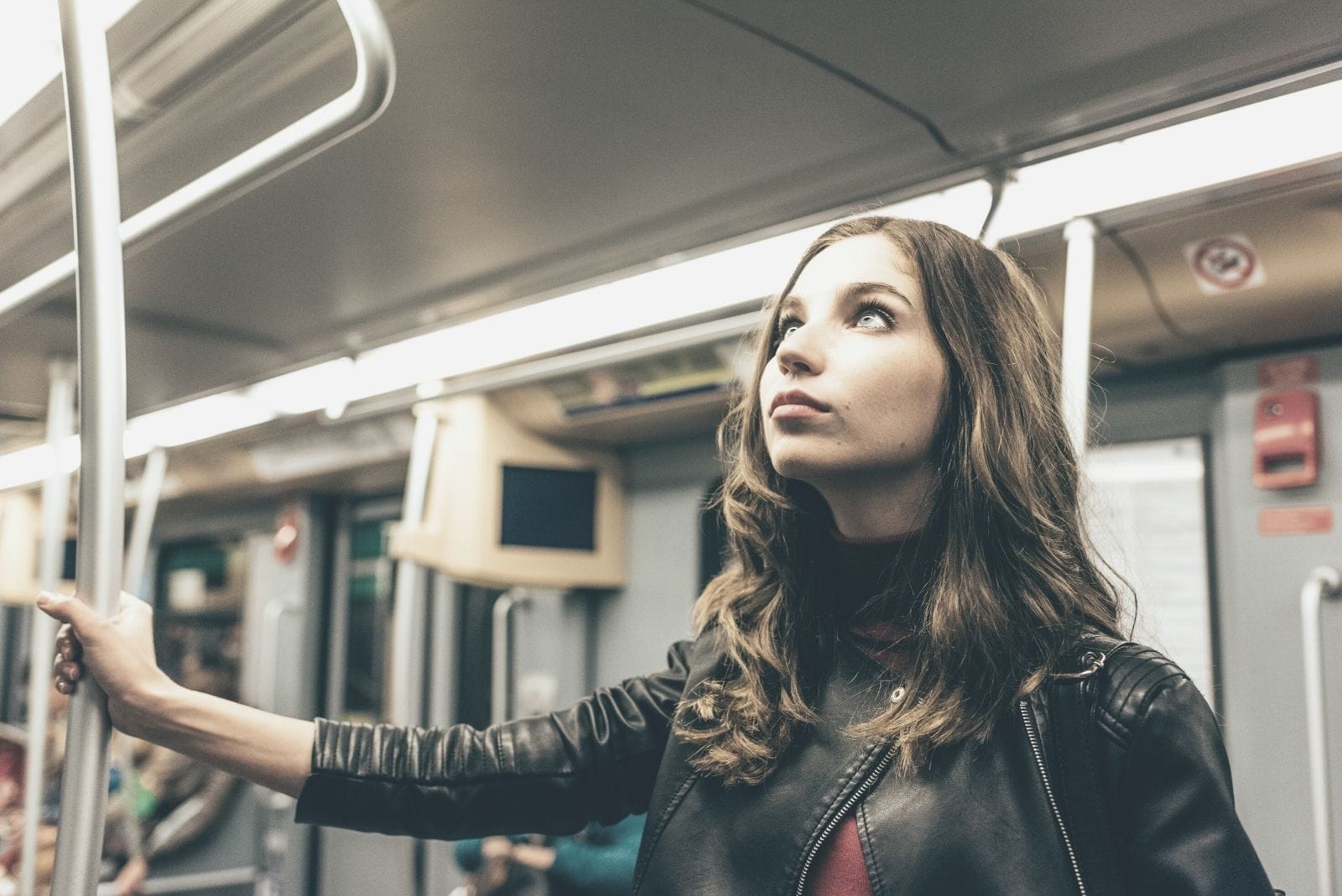 donna pensierosa che viaggia in metropolitana in piedi e tenendo la ringhiera con lo sguardo rivolto verso l'alto