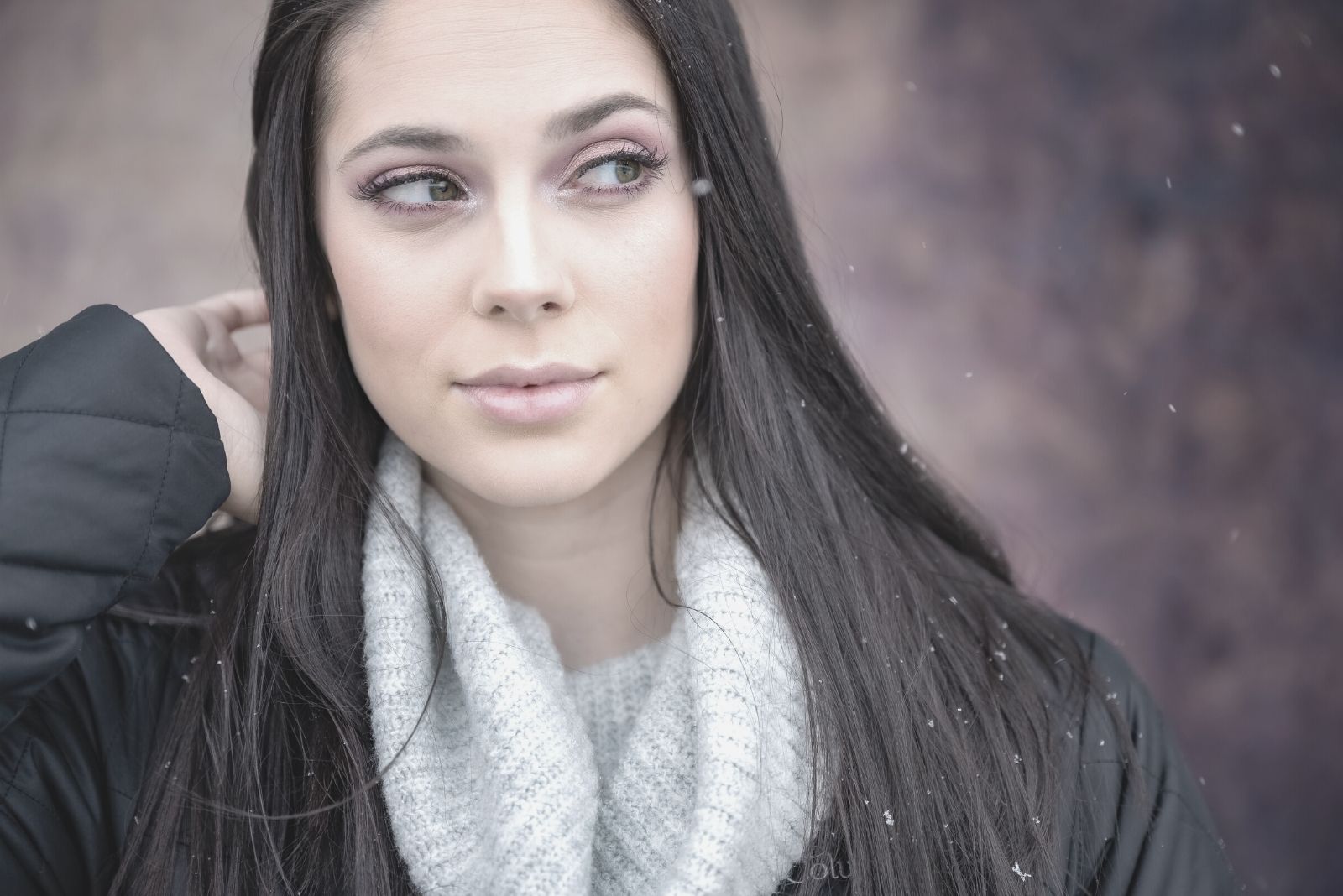 mulher pensativa, com lenço branco e casaco preto, olhando de lado para a câmara