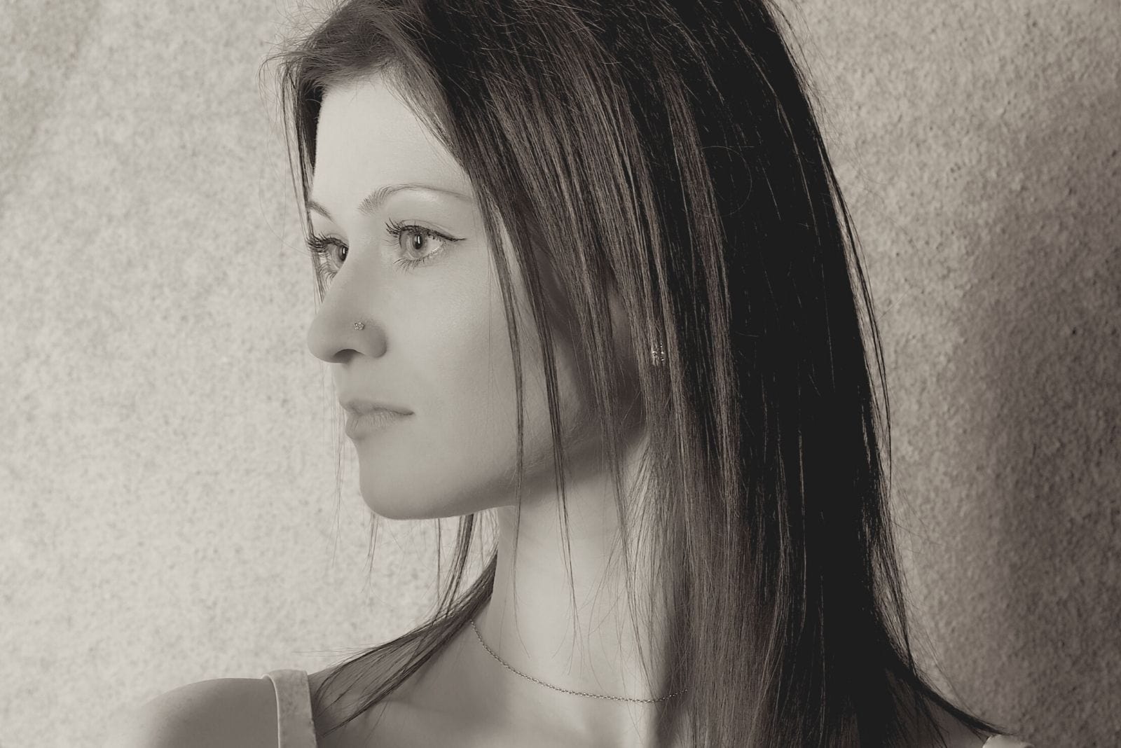pensive young woman standing againsta a gray stoned background 