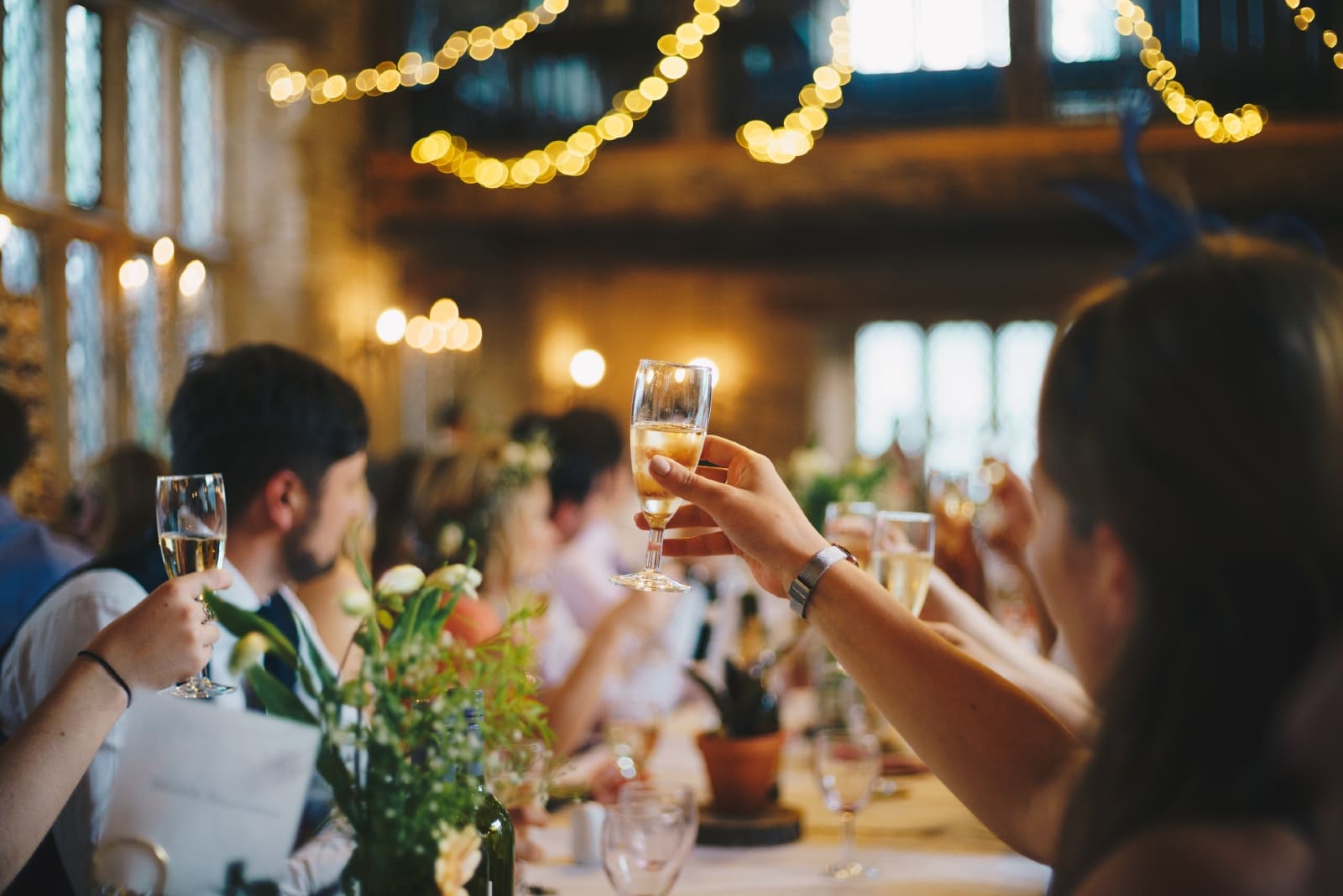 personas levantando copas de vino sentadas a la mesa