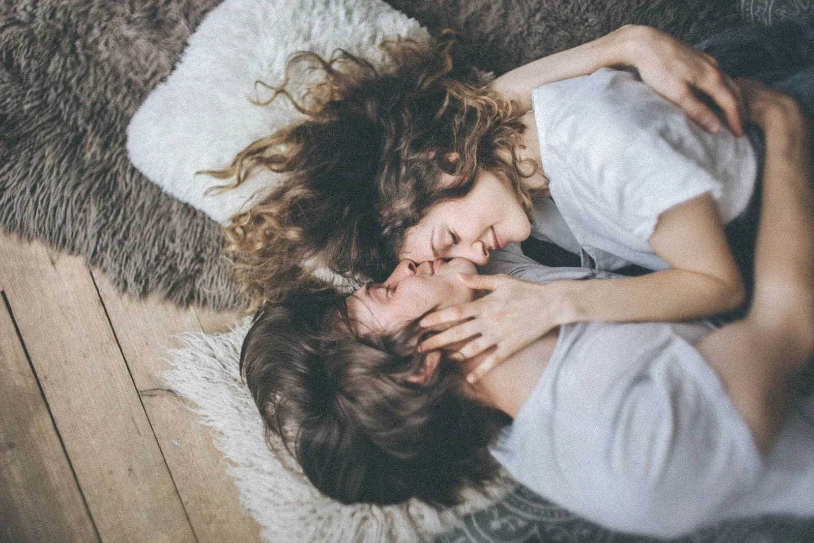 photograph of a couple in love lying down on the floor with carpet man kissing the forehead of the woman