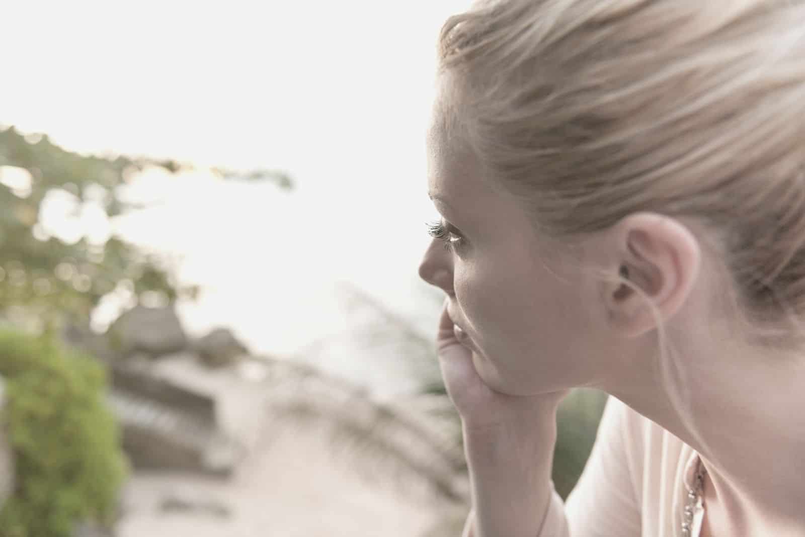 portrait of a pensive lady with hand supporting her head looking away outdoors