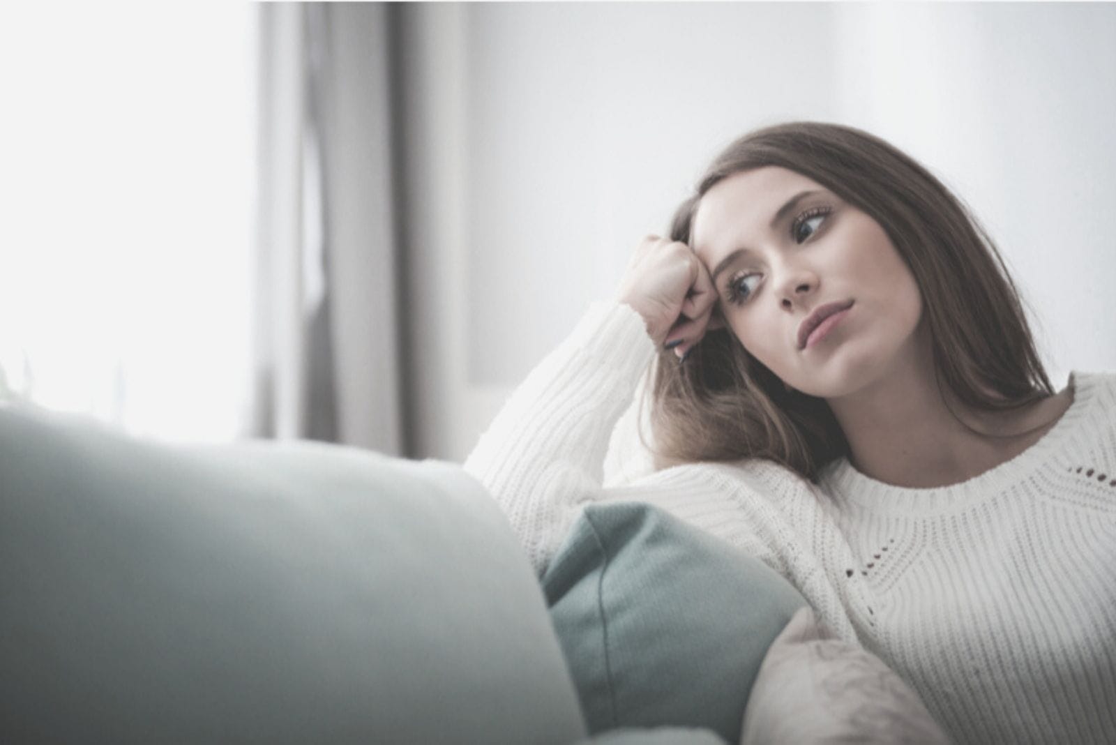 mujer bonita descansando en el sofá y pensando profundamente dentro de la sala de estar