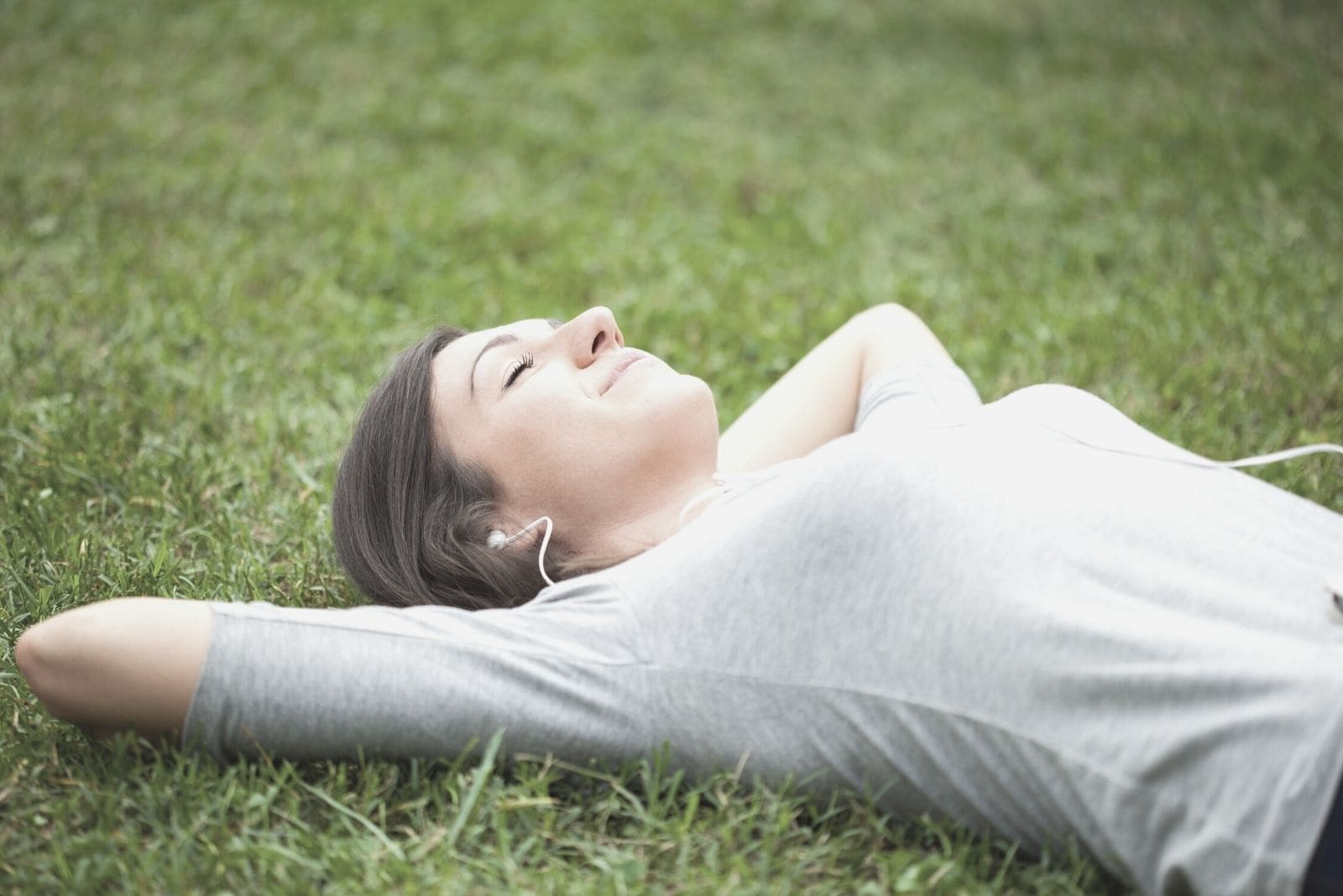 mujer relajada escuchando música tumbada en la hierba