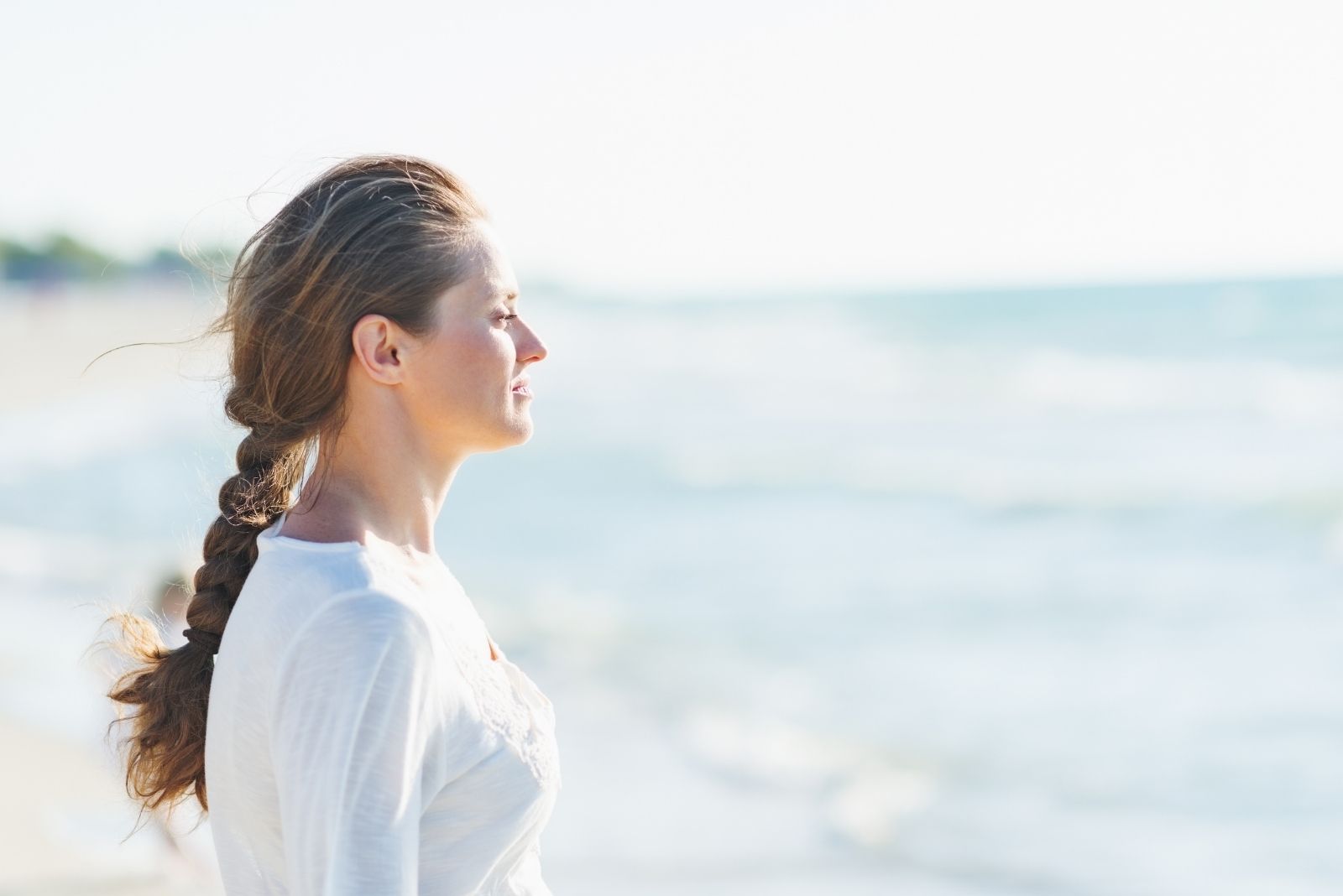 relaxed woman standing and facing the calm blue sea