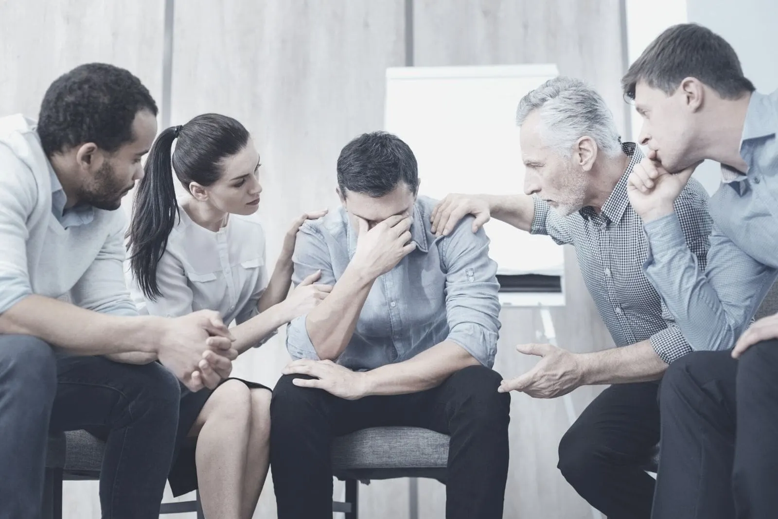sad man crying in between colleagues listening to his story inside the office