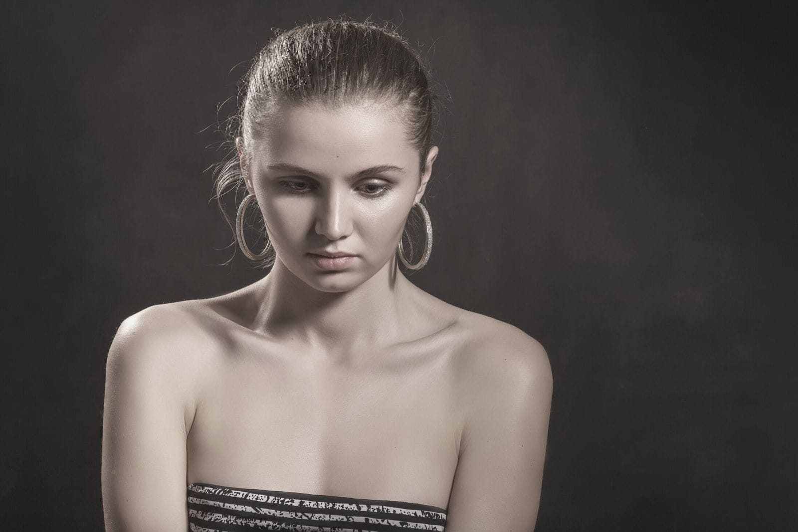 sad pensive girl on black background wearing big earrings