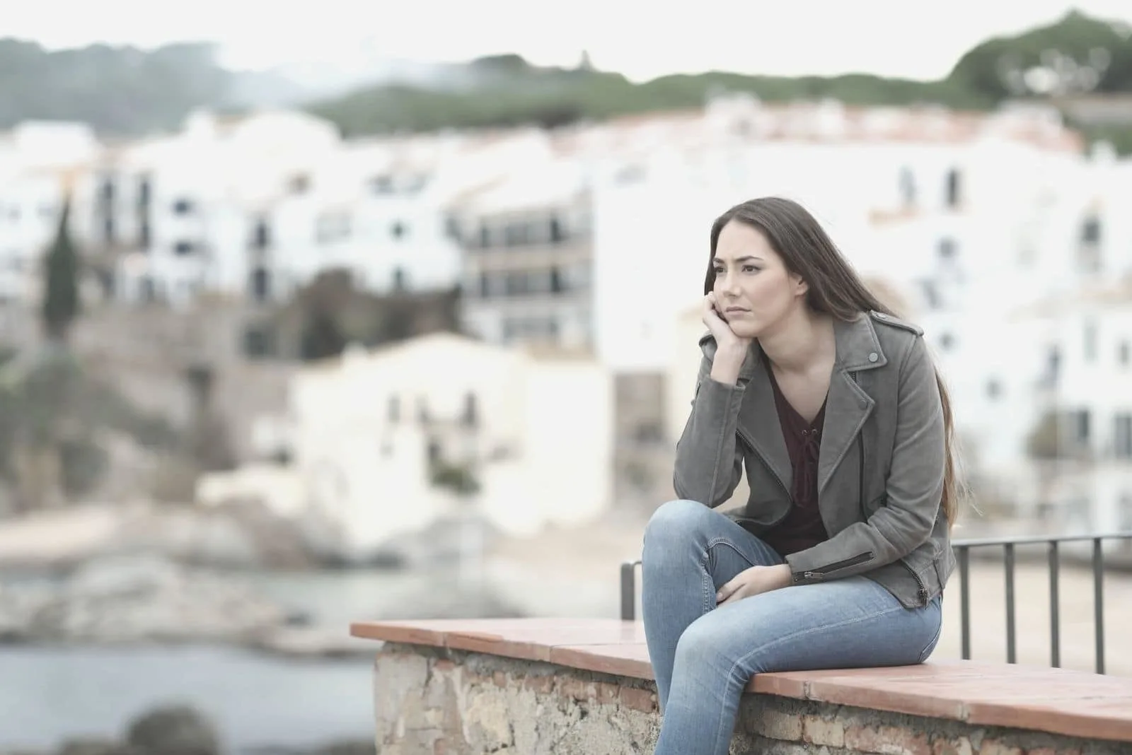 sad pensive lady sitting outdoors looking at the town