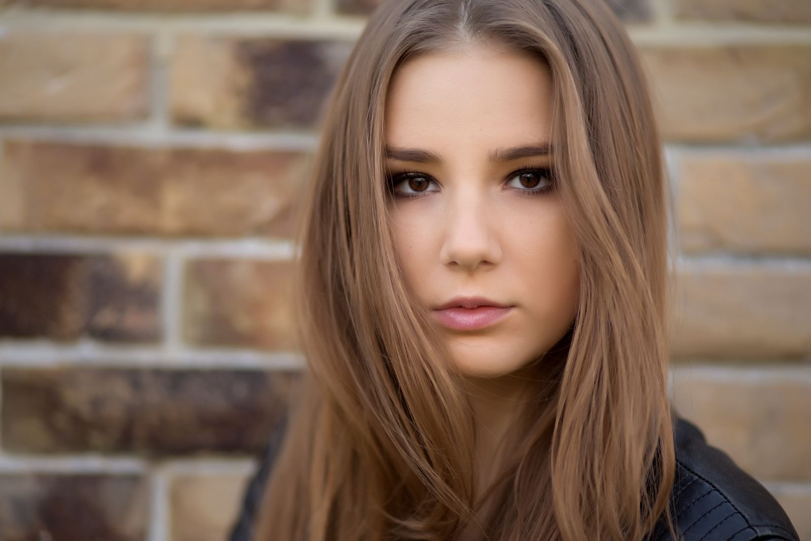 sad woman looking at the camera in close photography near the brick wall