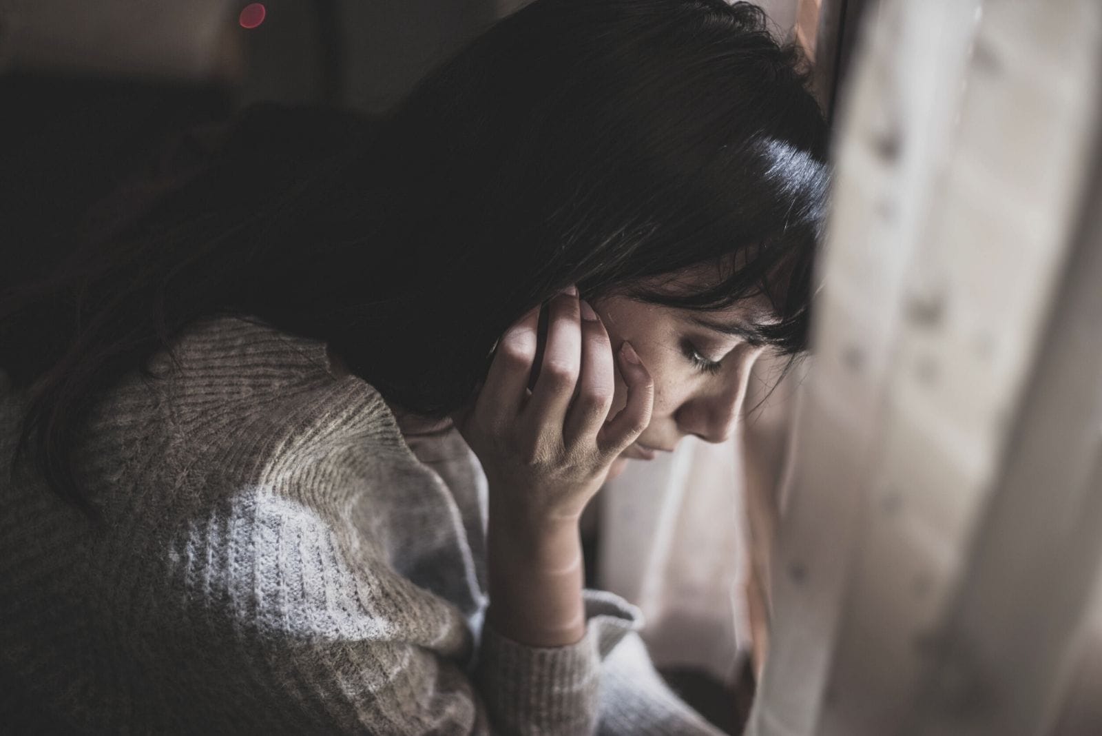 mujer triste pensando profundamente en ángulo alto agarrándose la oreja y mirando hacia abajo