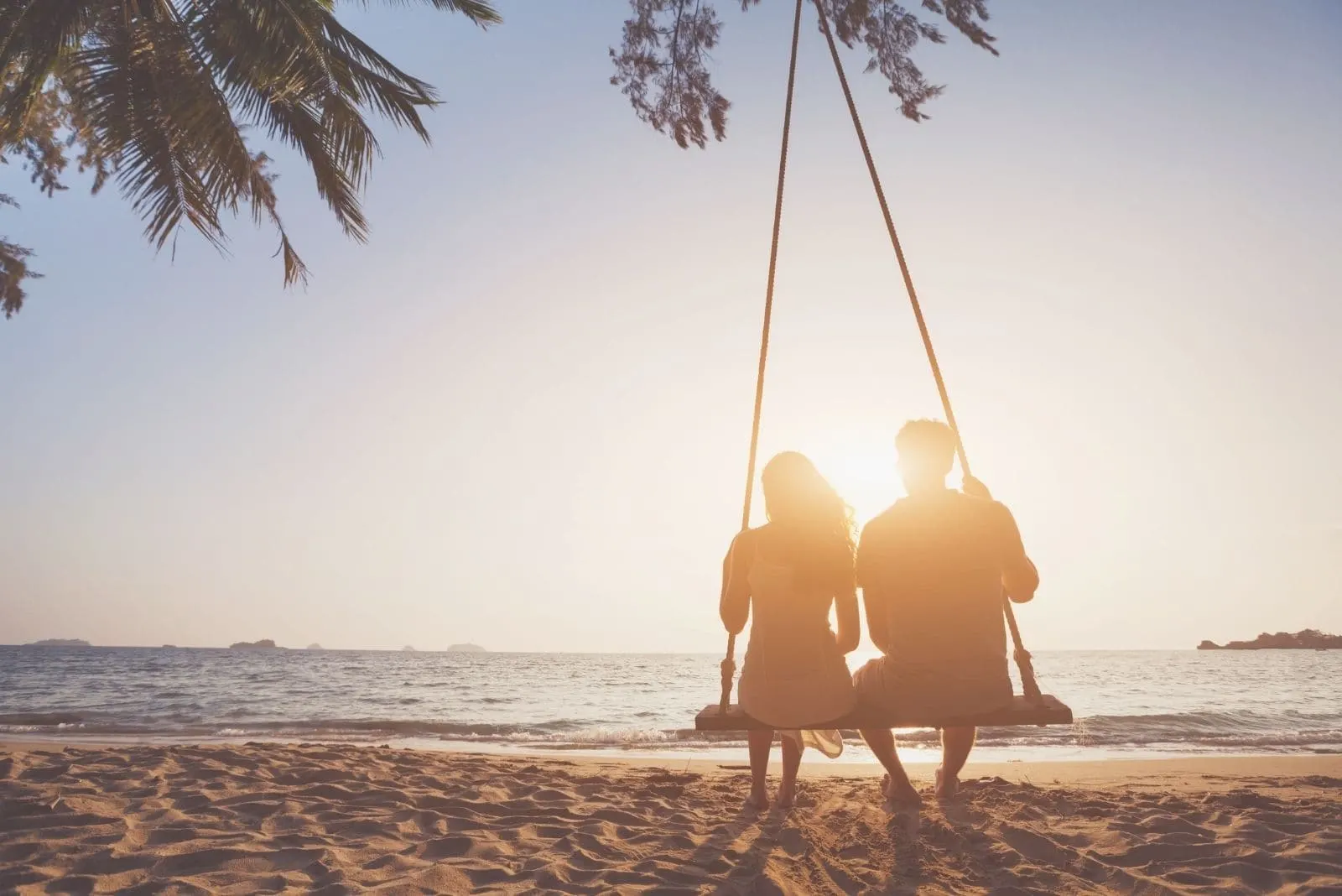 silhouette of a couple in love on a honeymoon sitting on the swing in the beach