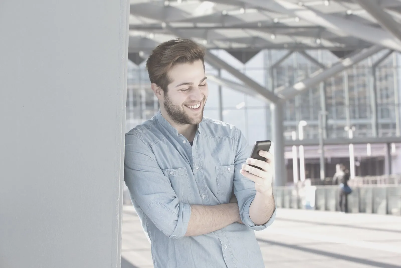 smiling man reading text messages from his phone outside a store