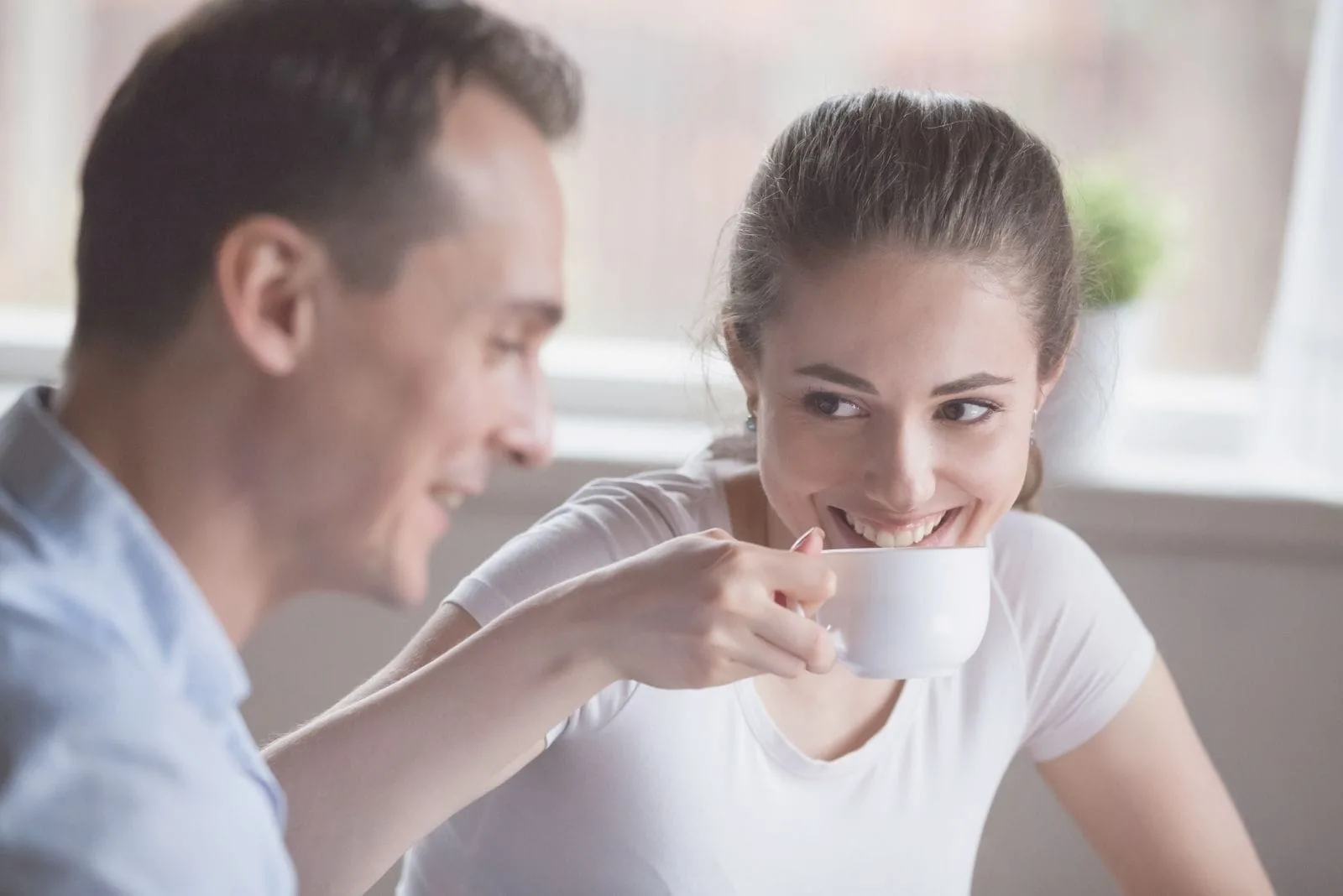 smiling woman drinking coffee with a handsome man indoors
