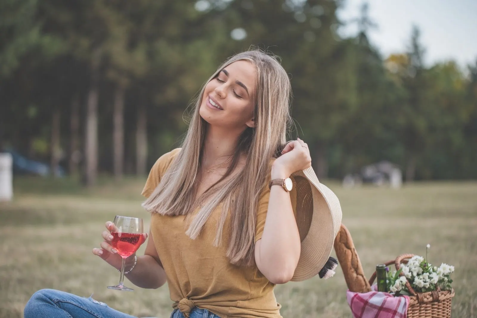 smiling woman in picnic at the park having a good time holding wine