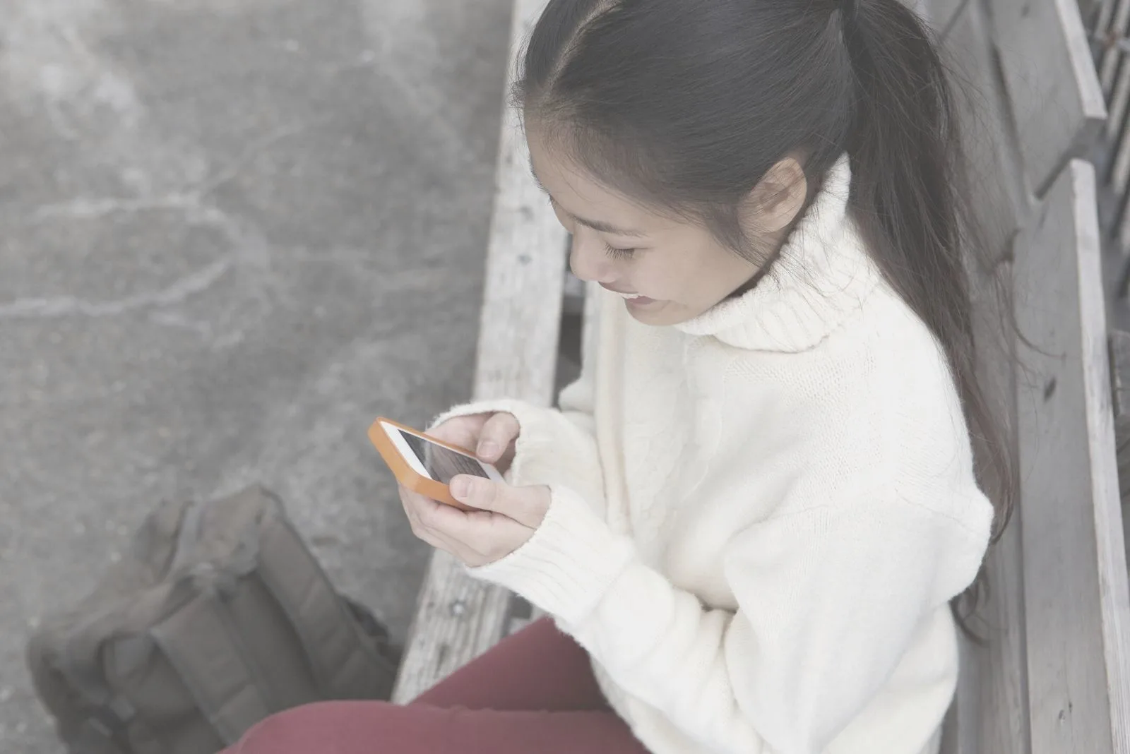 top angle of a woman smiling while texting and sitting outdoors