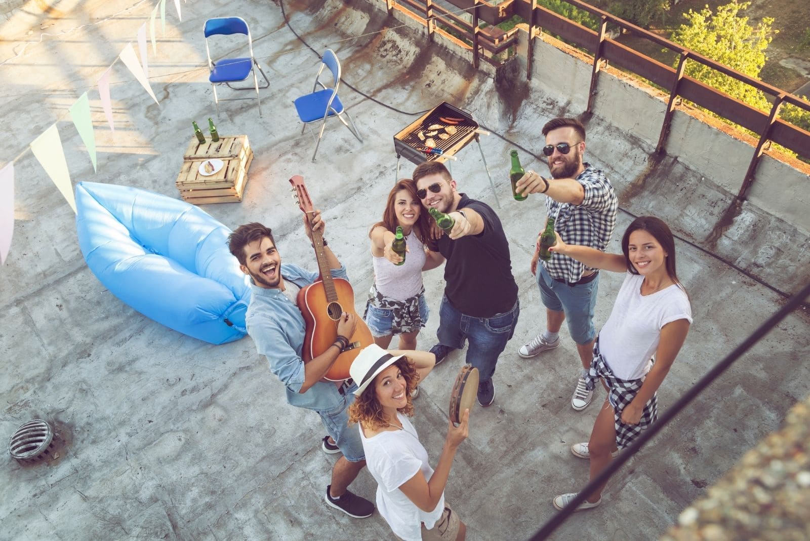 vista superior de um grupo de amigos a beber e a tocar guitarra numa festa no telhado