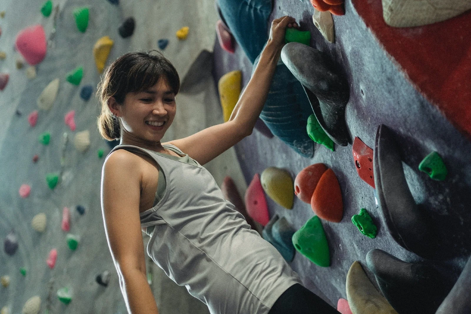 happy woman in gray top climbing wall
